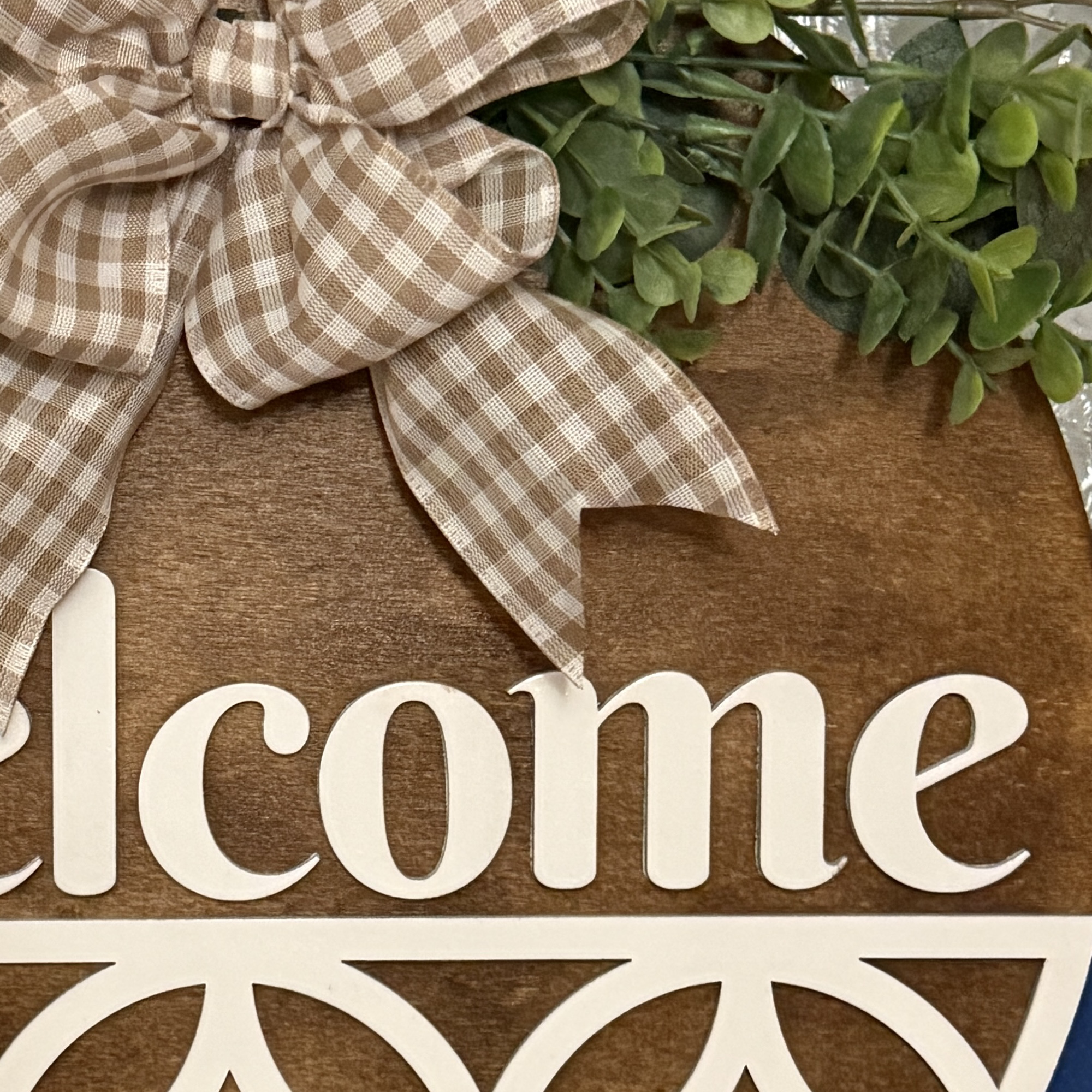 Close-up of layered wood design showing “Welcome” script and cutout pattern details
