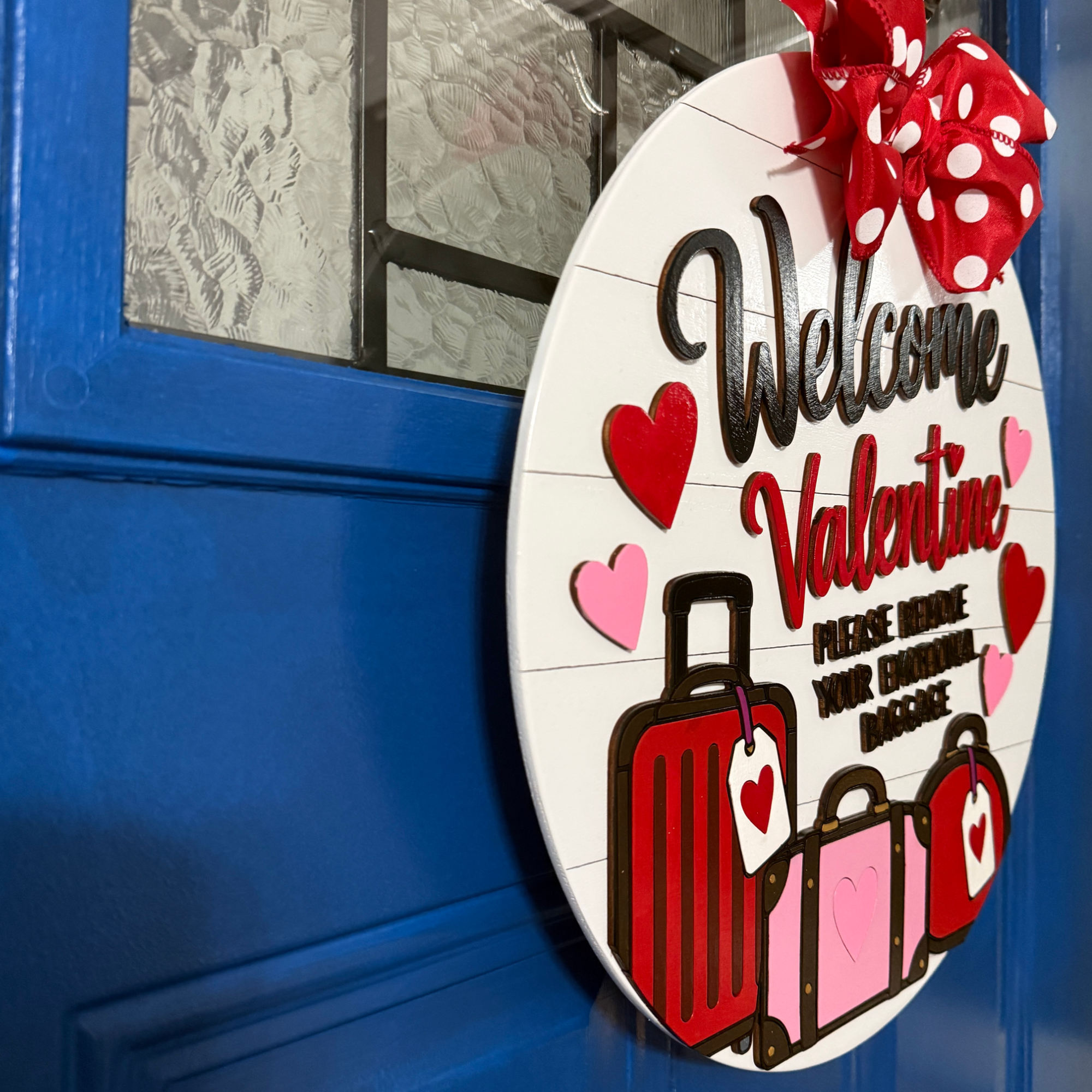 Angled view of funny Valentine door hanger with layered luggage, hearts, and emotional baggage saying