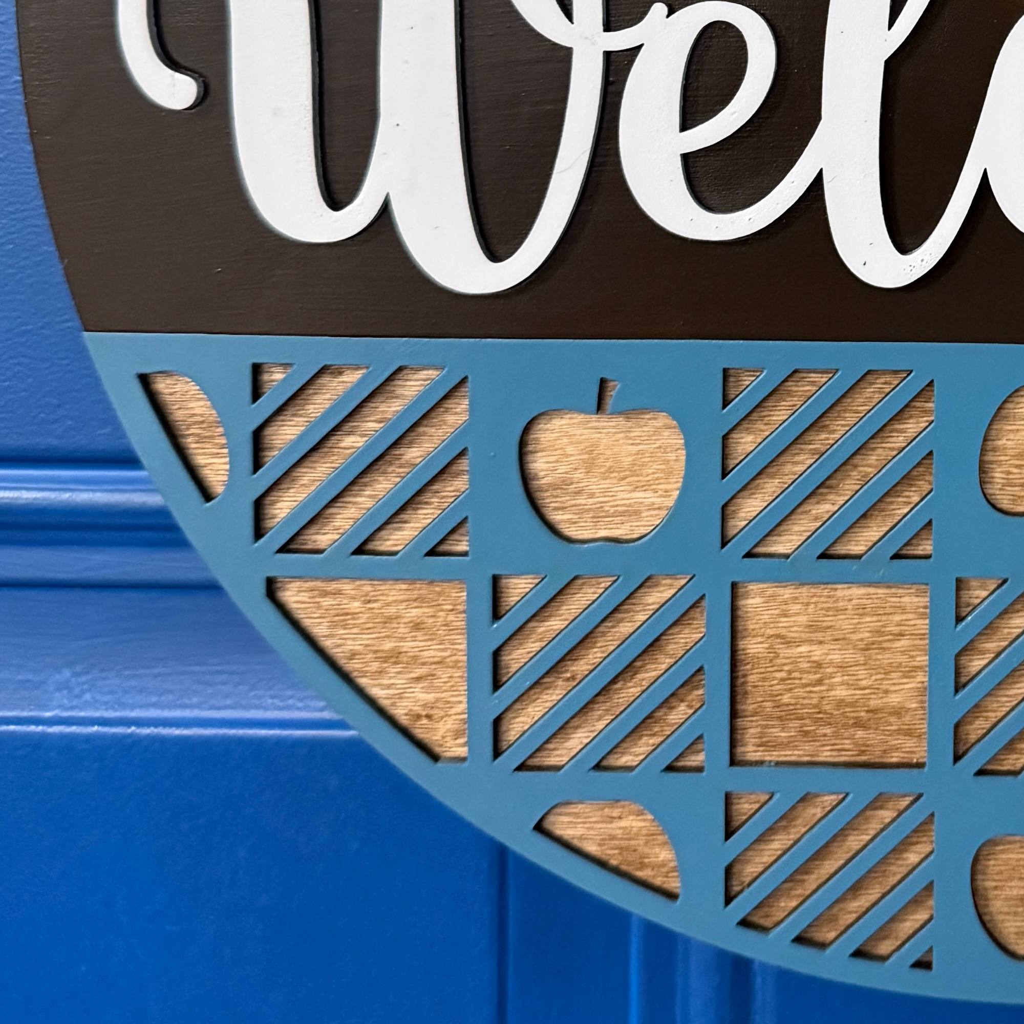Close-up of “Welcome” script lettering in white on brown band
