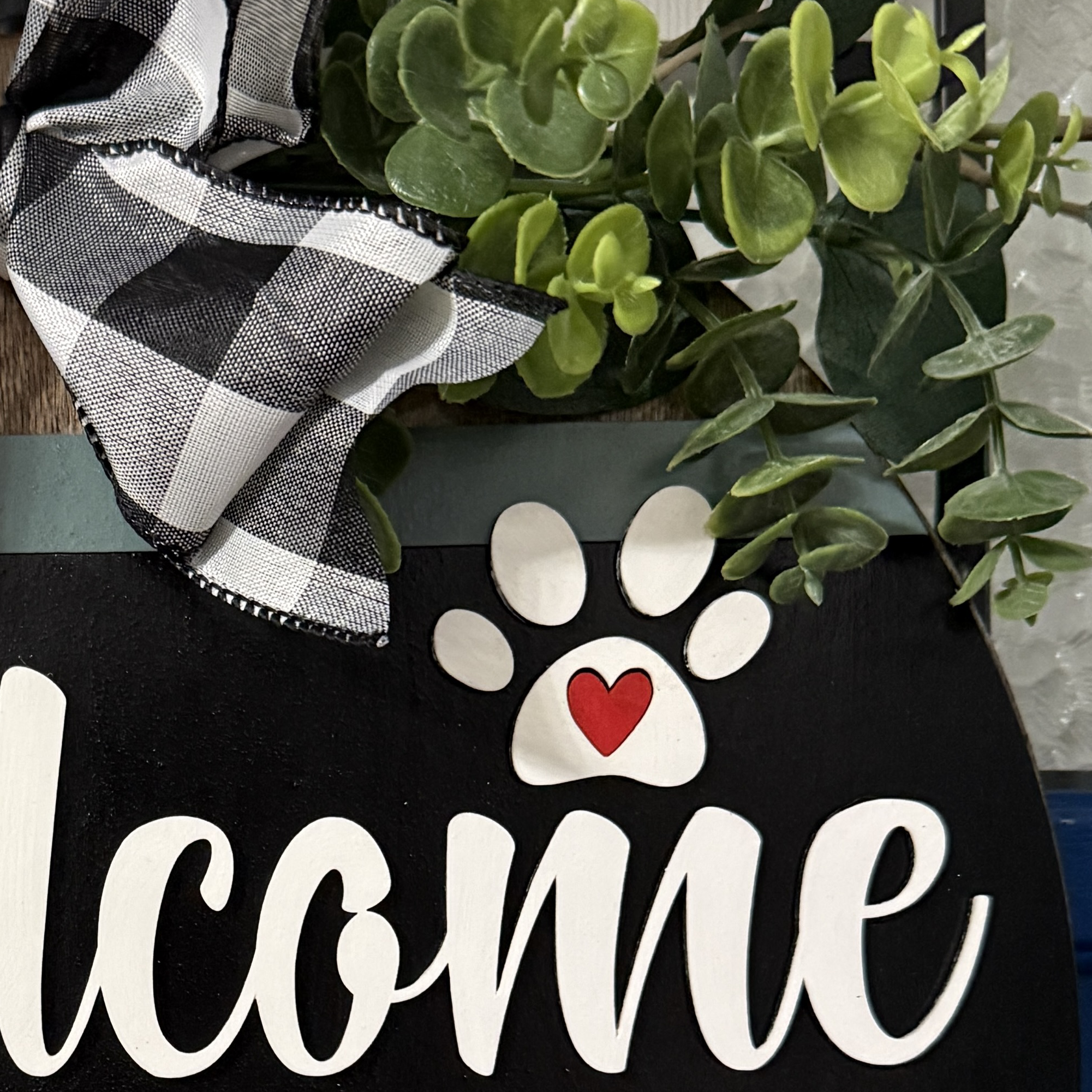 Close-up of “welcome” text with paw print and red heart detail on black background