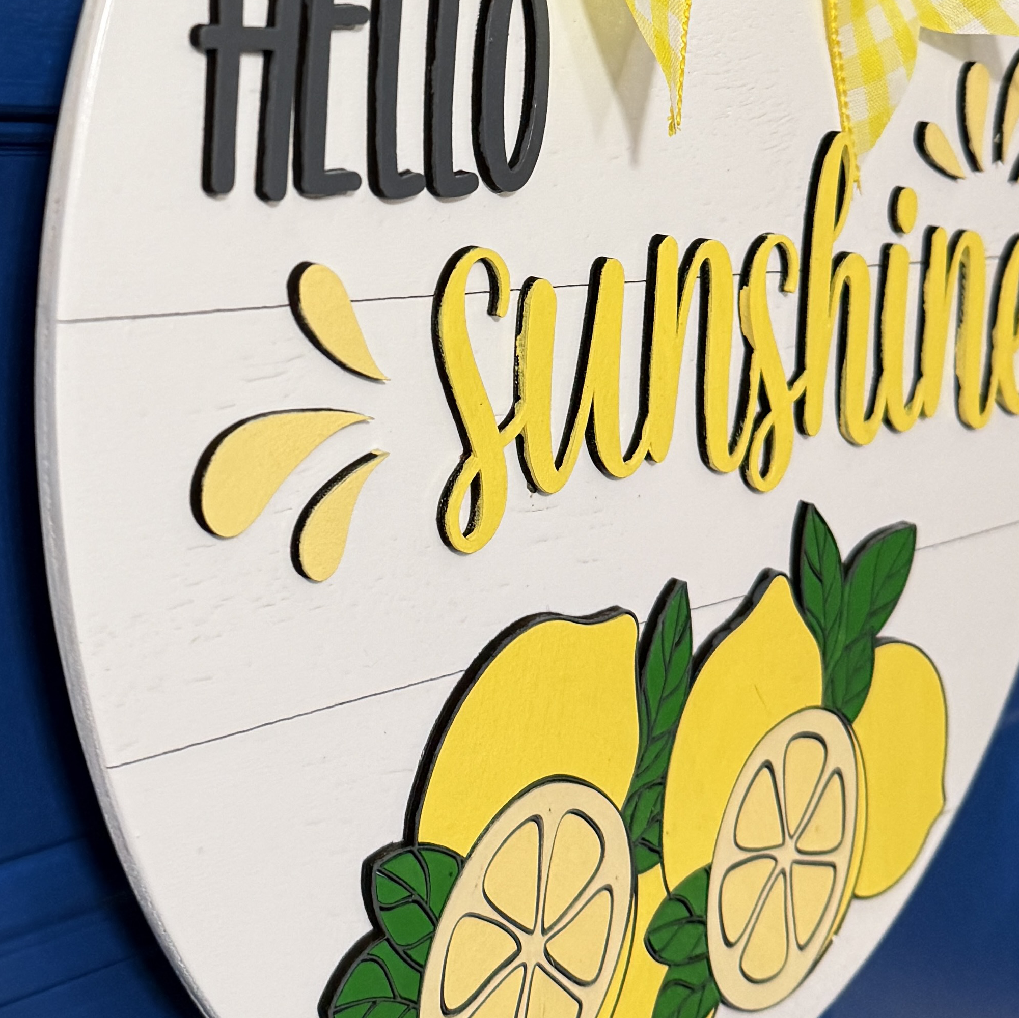 Side angle view of dimensional lettering and layered lemon illustration on round summer front door decor