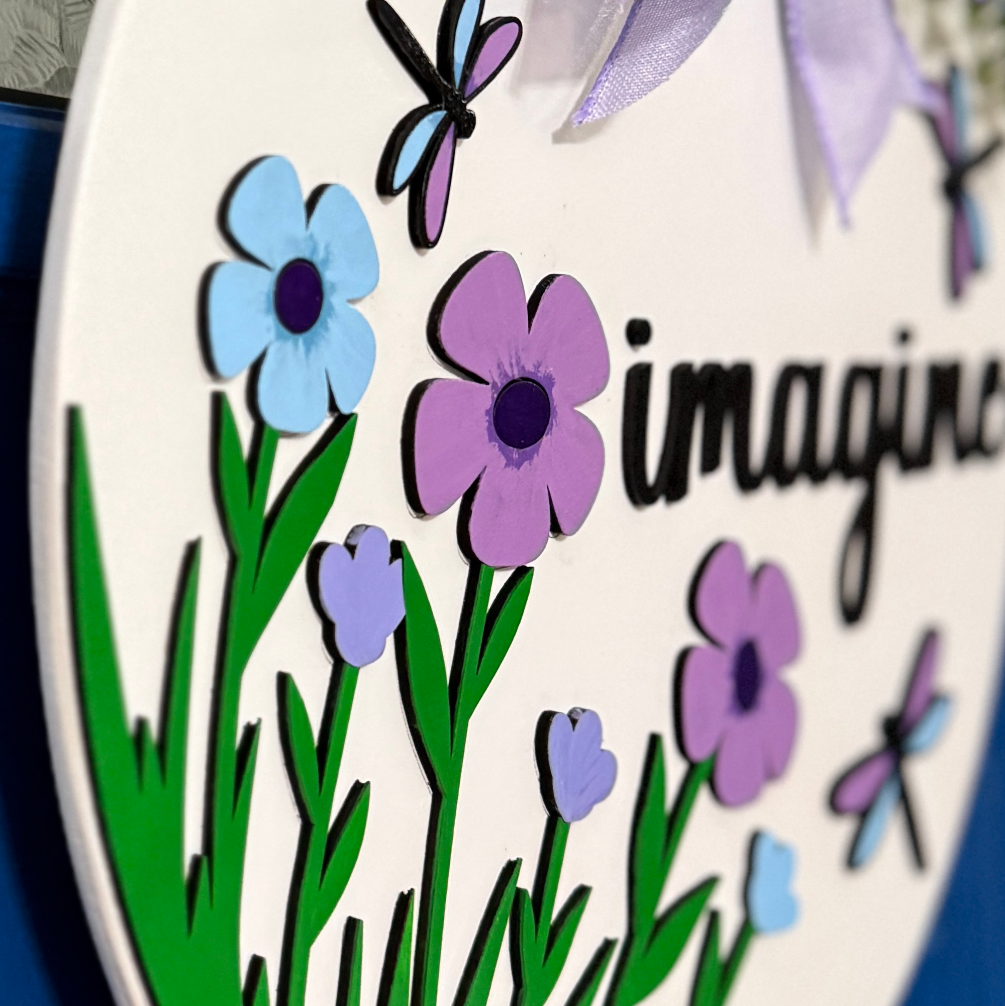 Side angle detail of layered flowers and dragonfly elements highlighting dimensional wood construction