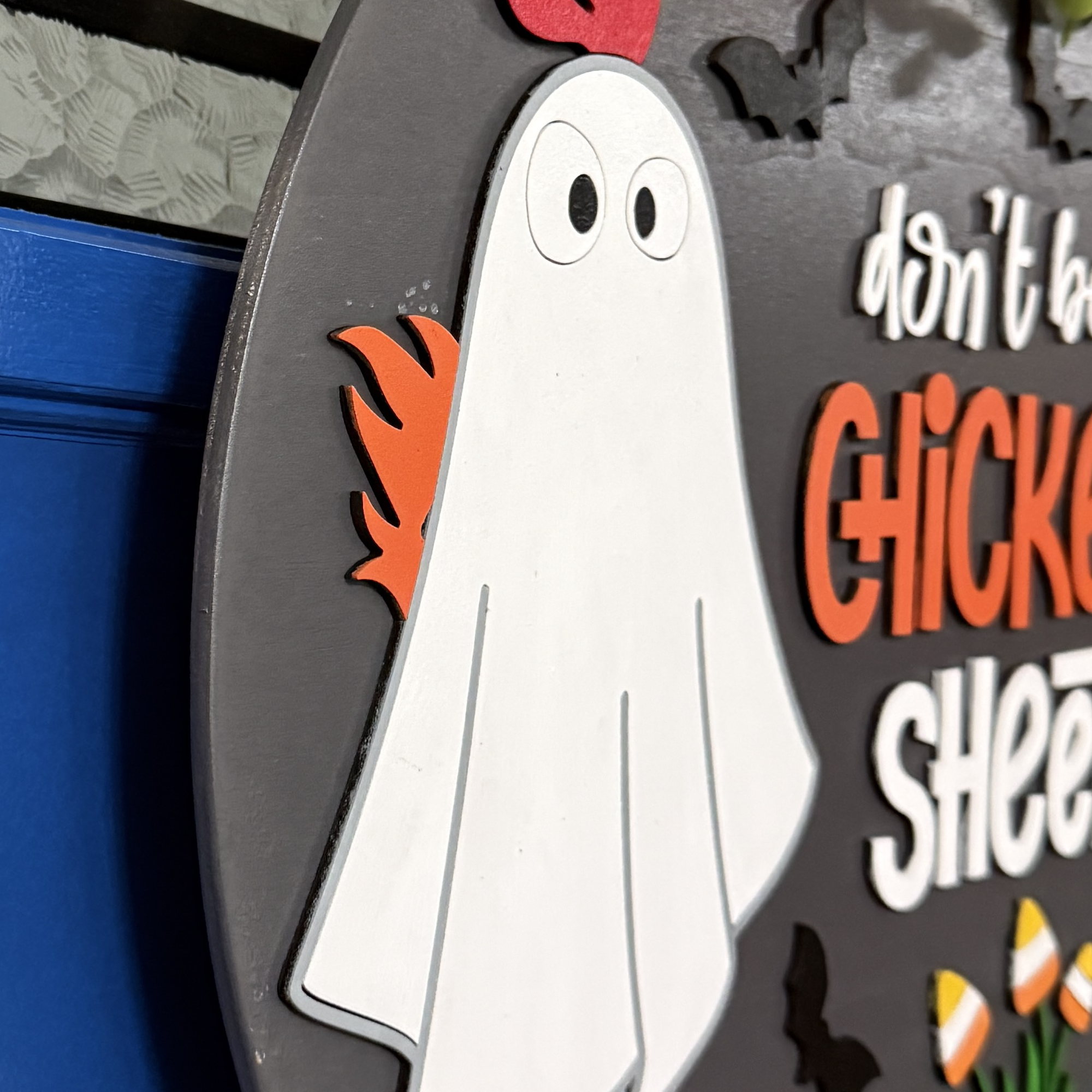 Close-up of ghost chicken character, candy corn, and jack-o’-lantern accents on the Halloween door hanger