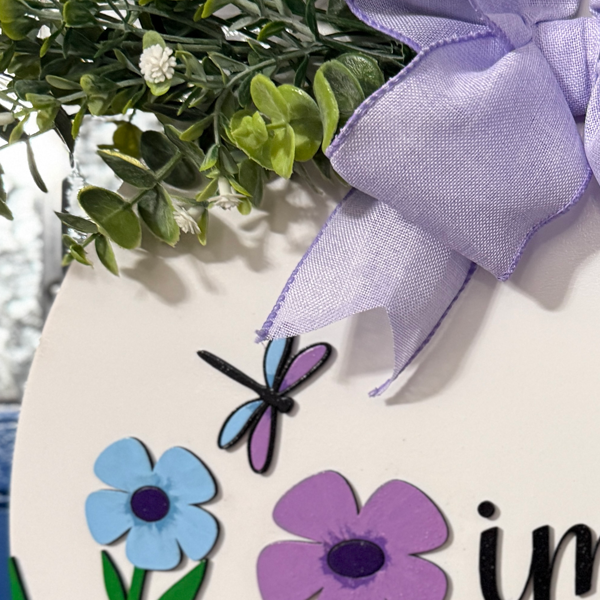 Close-up of lavender bow and greenery at top of floral door hanger with soft ribbon detail