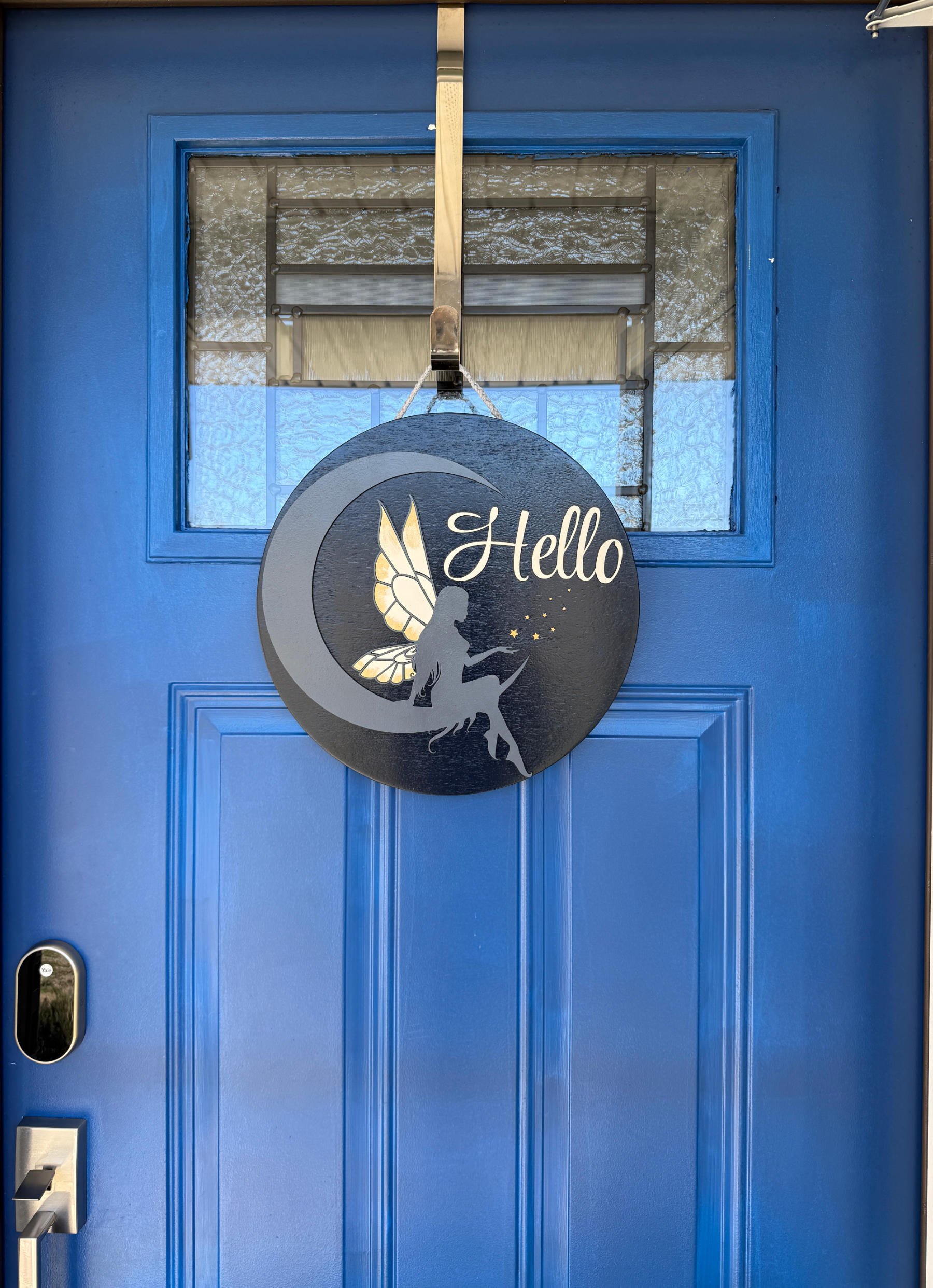 Wide shot of 14 inch round fairy moon hello door hanger displayed on blue front door