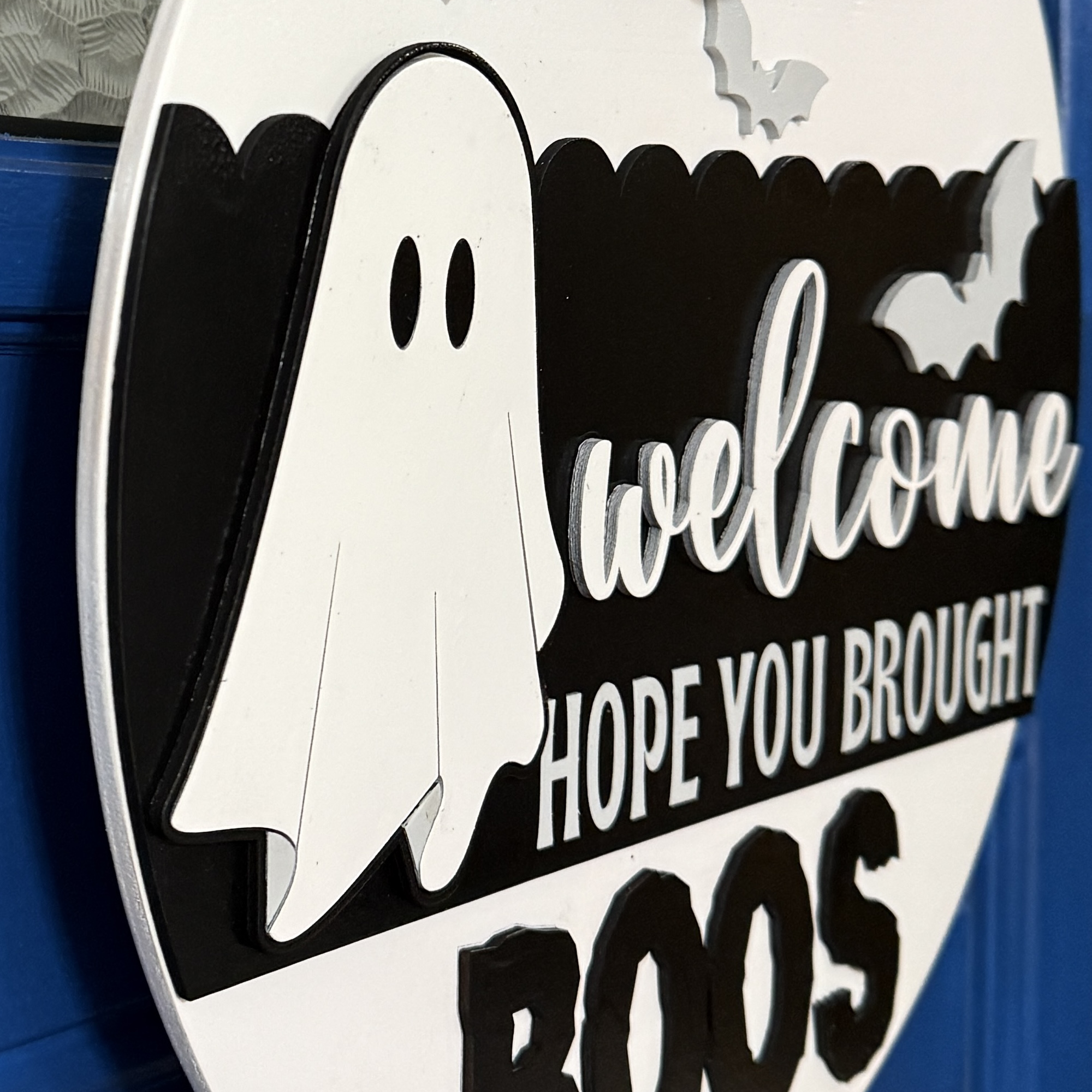 Close-up view of Halloween door hanger highlighting ghost graphic, bats, and buffalo plaid bow