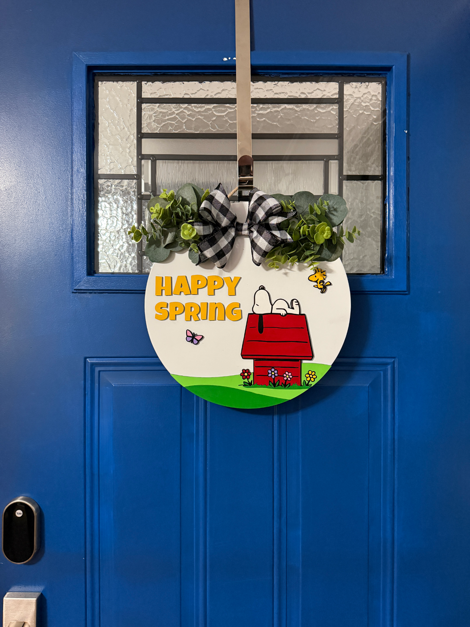 Full view of round spring sign with doghouse scene, flowers, and “Happy Spring” lettering