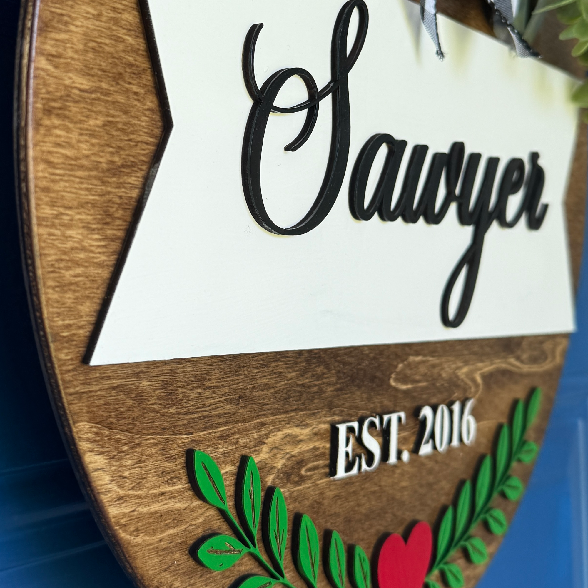 Close-up of custom family name sign with raised wood lettering.