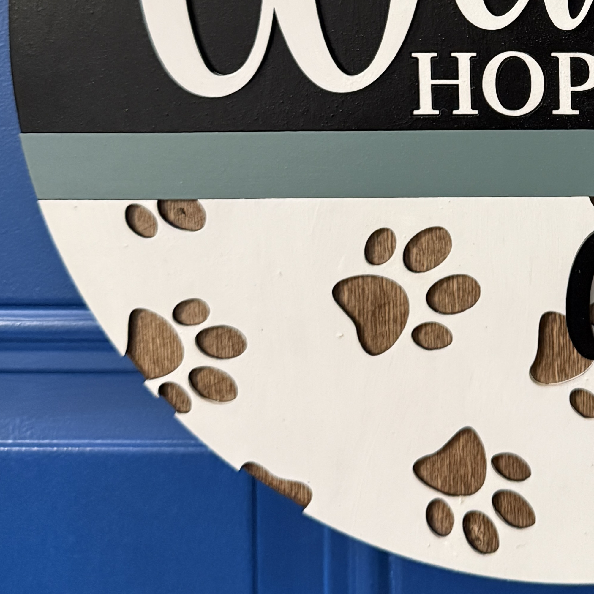 Close-up of lower half of sign with engraved paw print pattern and white background