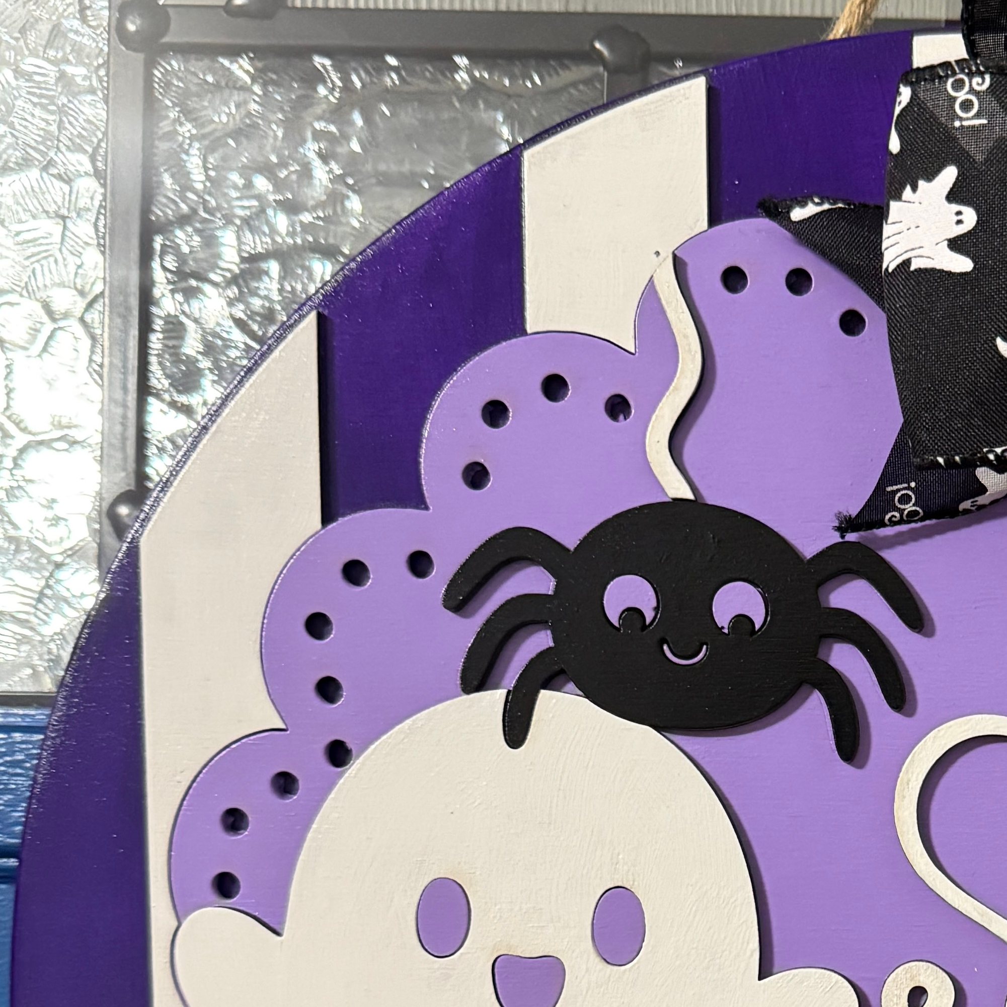 Close-up of layered purple and cream ghosts with black spider on Spooky and Sweet Halloween door hanger