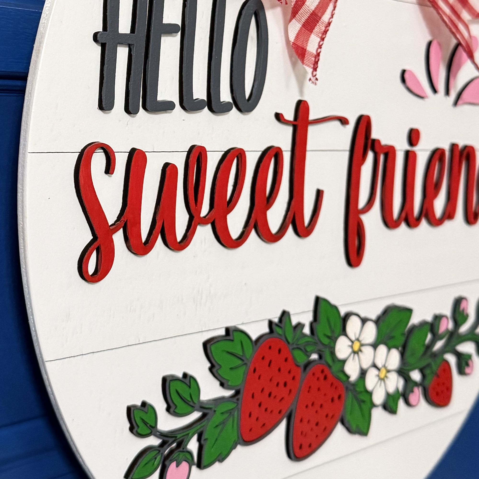 Side angle view of dimensional lettering and layered strawberry illustration on round summer front door decor