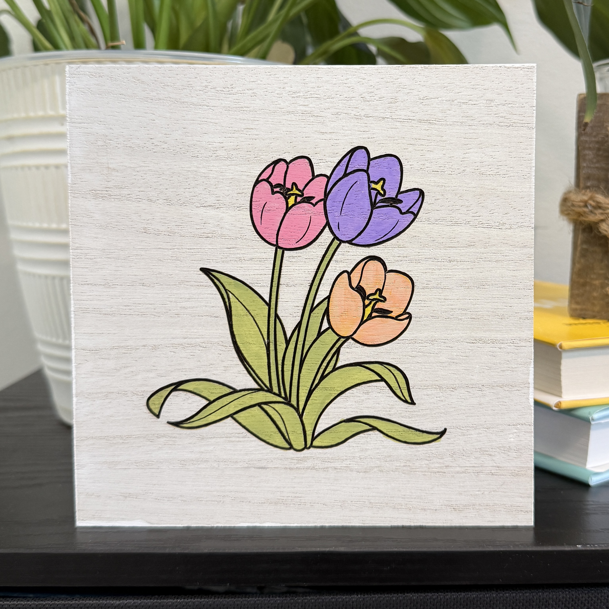 Hand-painted tulip wood shelf sitter featuring pink lavender and peach tulips displayed on a black shelf with white planter and greenery