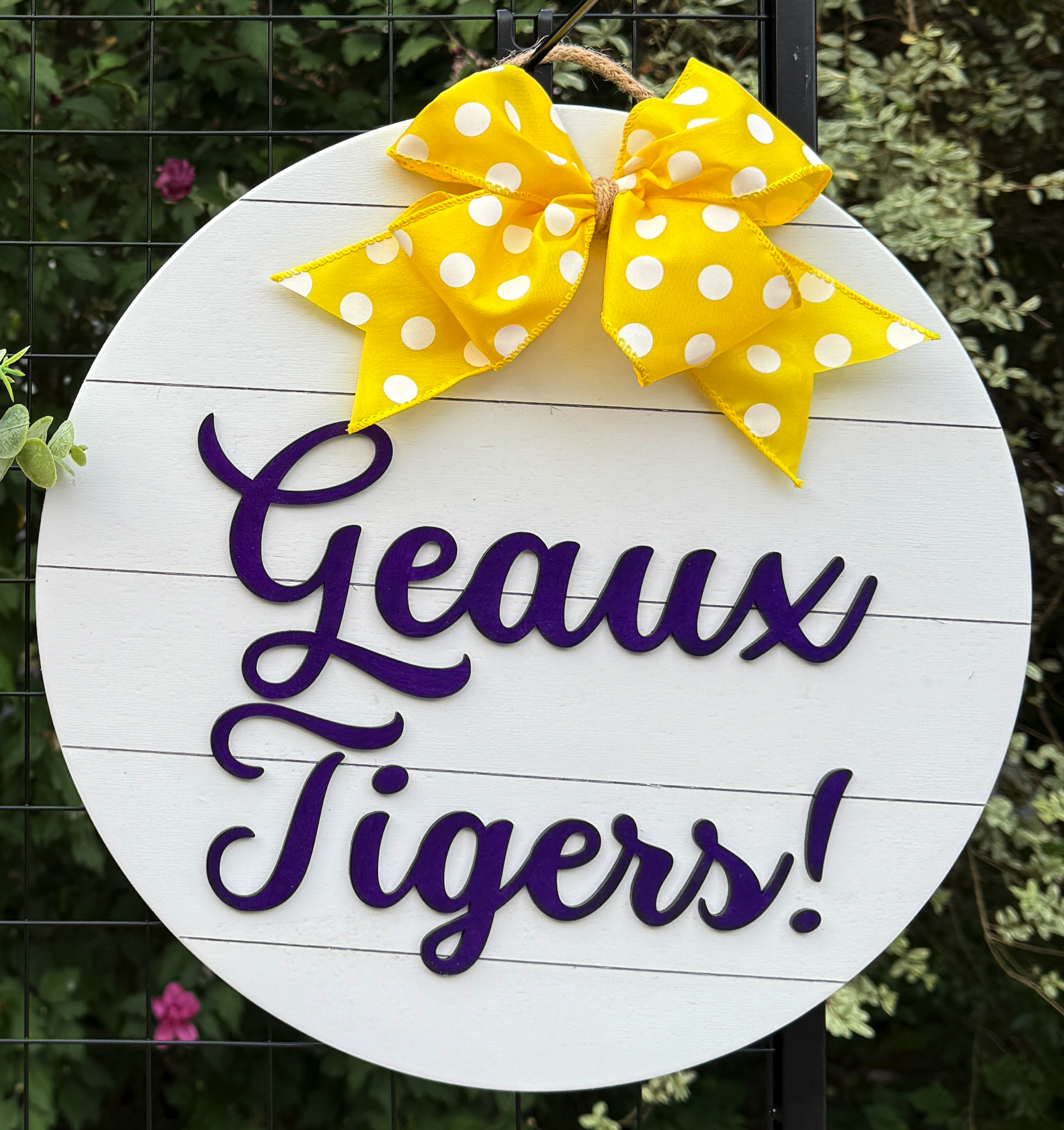 Round Geaux Tigers door hanger with bold purple script on white shiplap background and yellow polka-dot bow