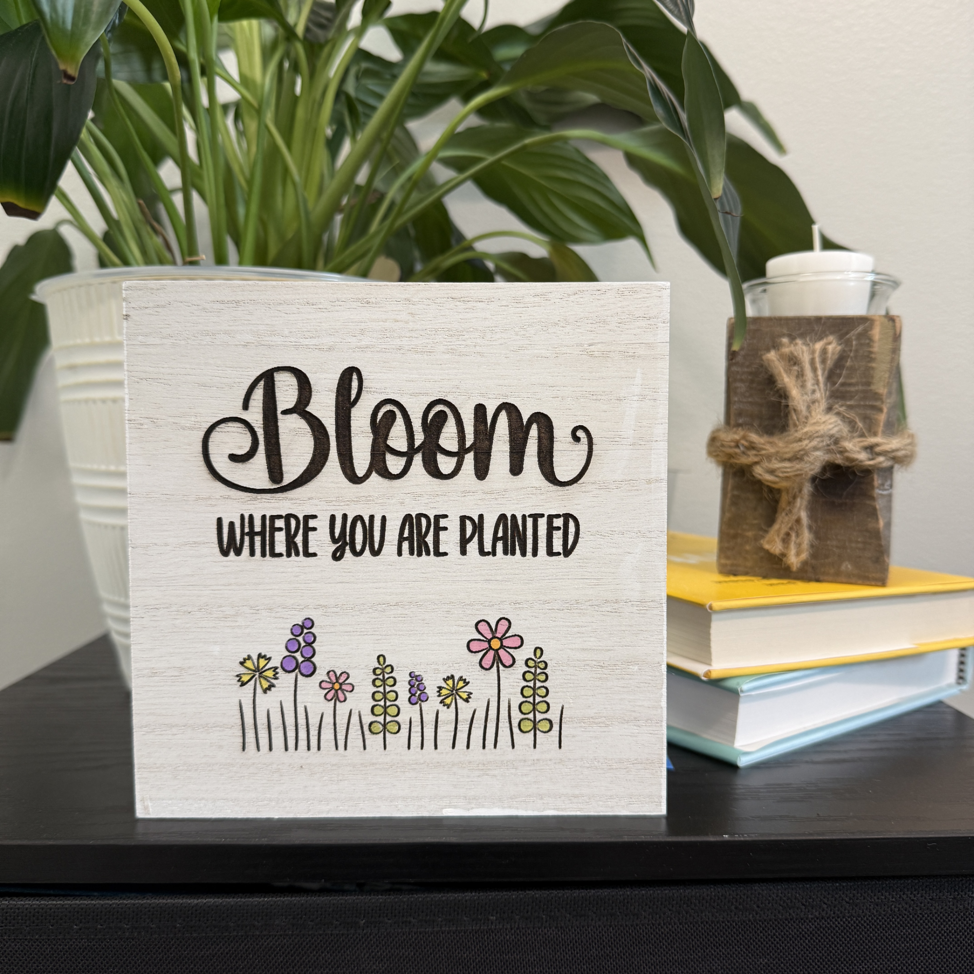 Inspirational Bloom Where You Are Planted wooden shelf sitter styled on a shelf with stacked books and potted plant