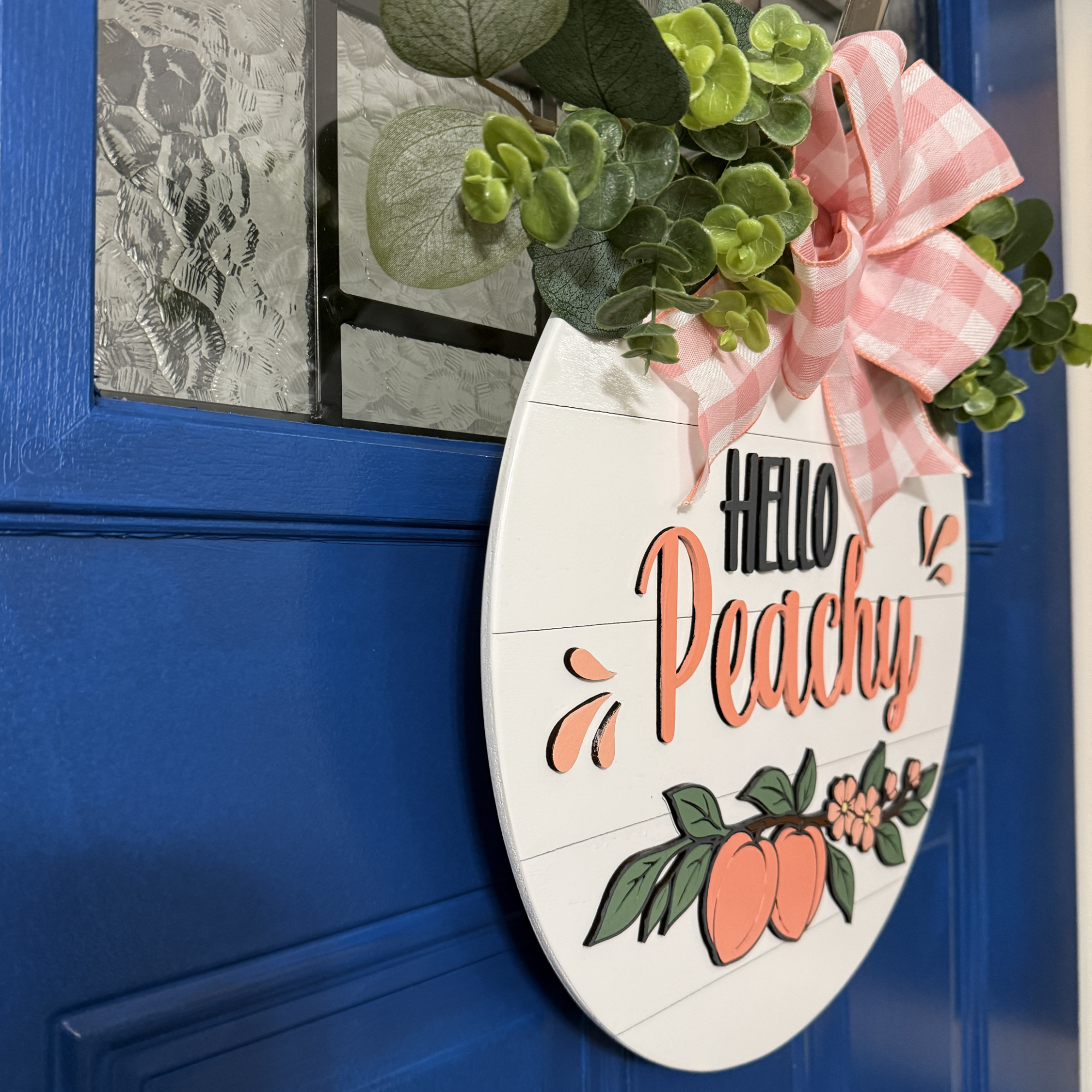 Angled side view of Hello Peachy summer door hanger showing layered thickness, greenery, and dimensional lettering