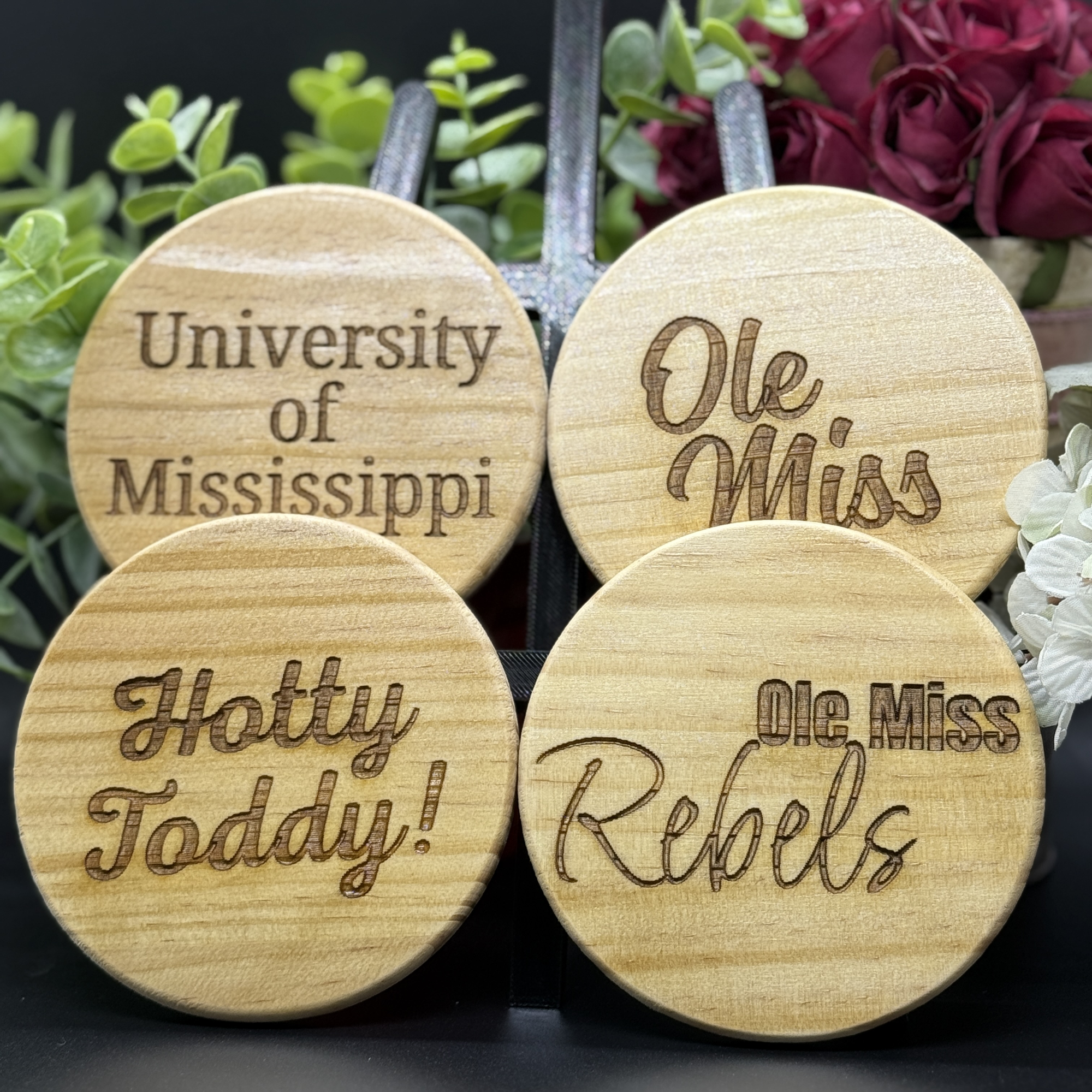Set of four round Ole Miss engraved wooden coasters with designs including University of Mississippi, Ole Miss, Hotty Toddy, and Ole Miss Rebels
