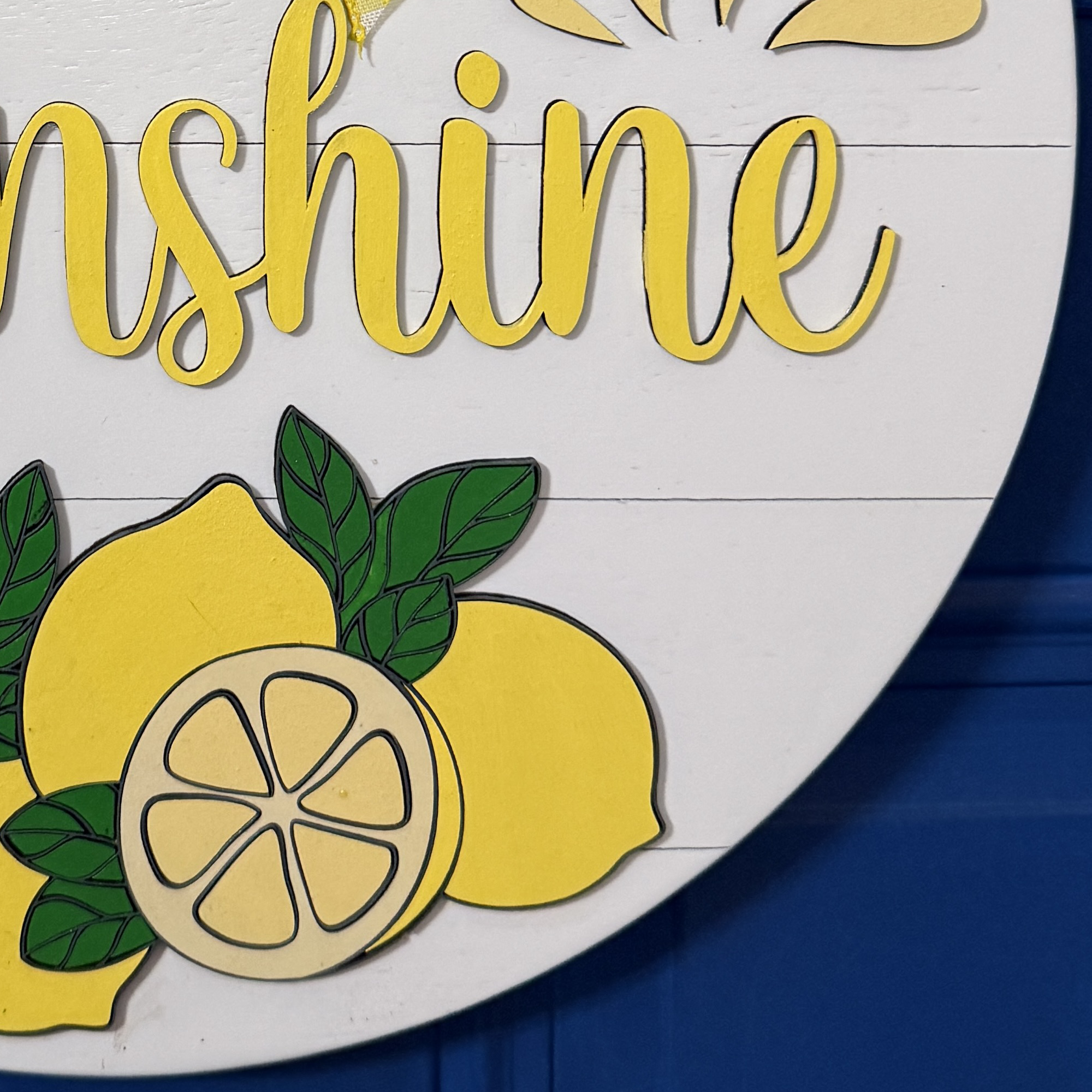 Detailed view of bright yellow lemons and citrus slice detail along bottom of Hello Sunshine door hanger