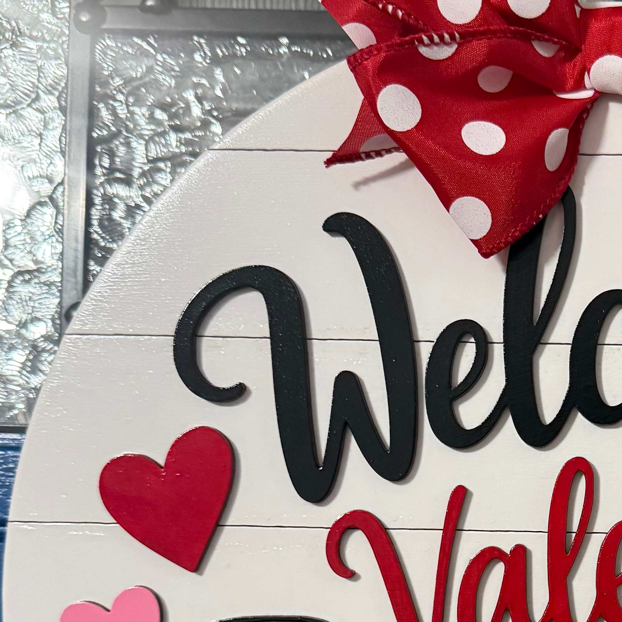 Close-up of layered Welcome Valentine lettering with red heart and red and white polka dot bow