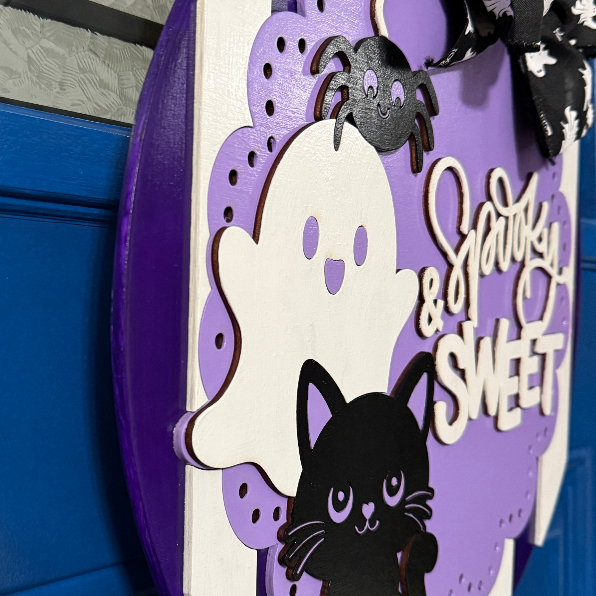 Close-up side view showing layered wood construction and dimensional details on purple Halloween door hanger