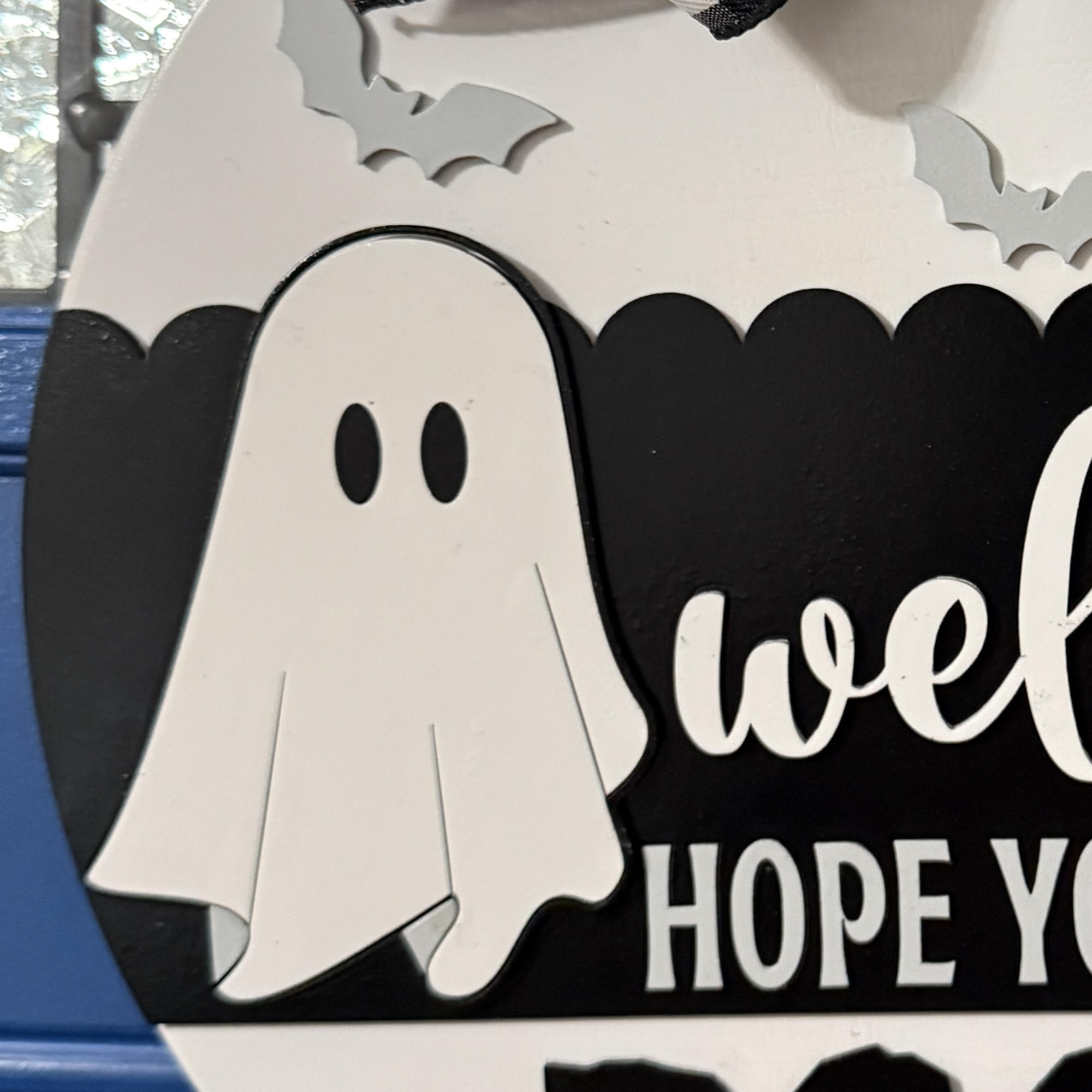 Close-up view of Halloween door hanger highlighting ghost graphic, bats, and buffalo plaid bow