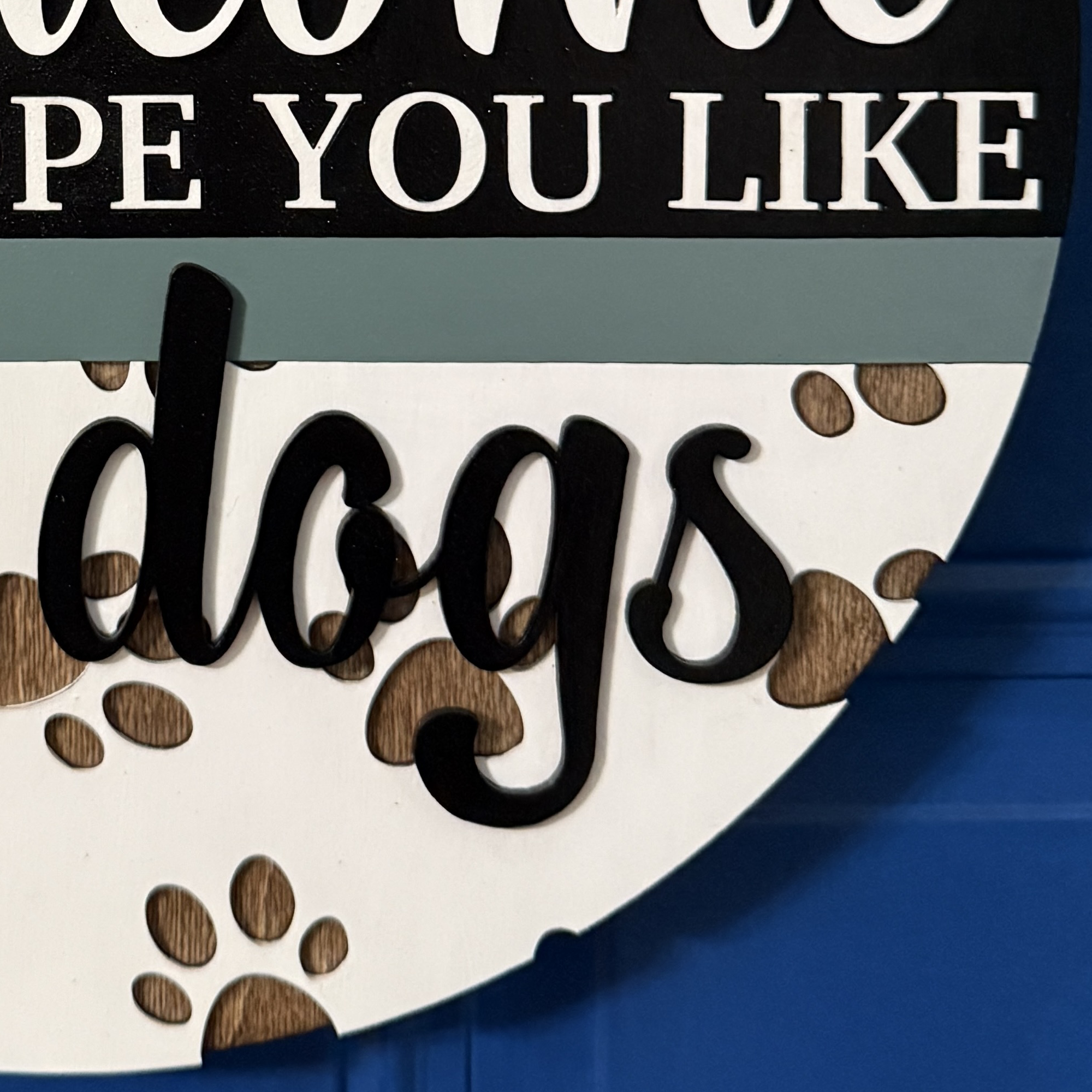 Close-up of “dogs” script text with layered wood lettering and paw print accents