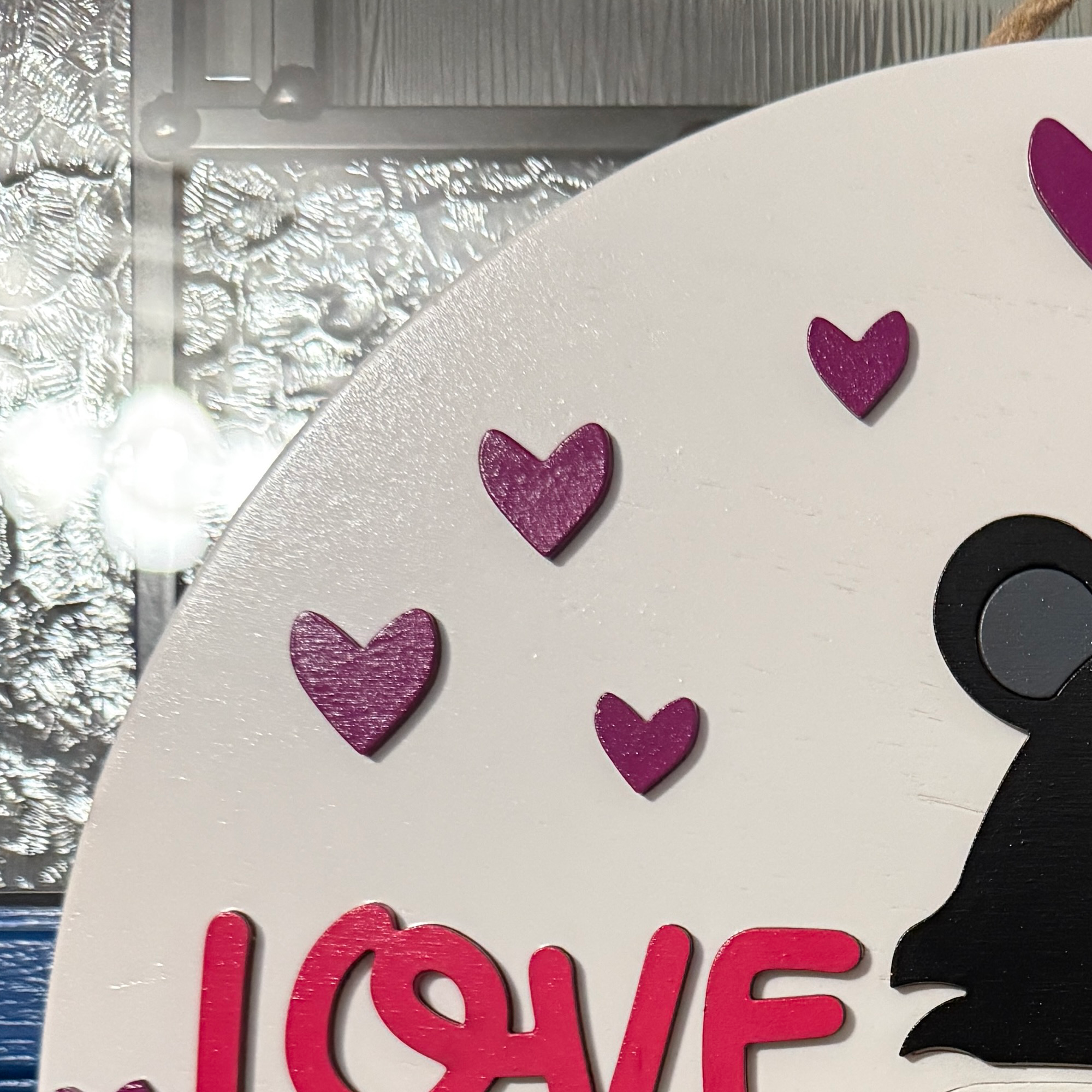 Close-up of pink Love lettering and purple heart accents on white Valentine door hanger