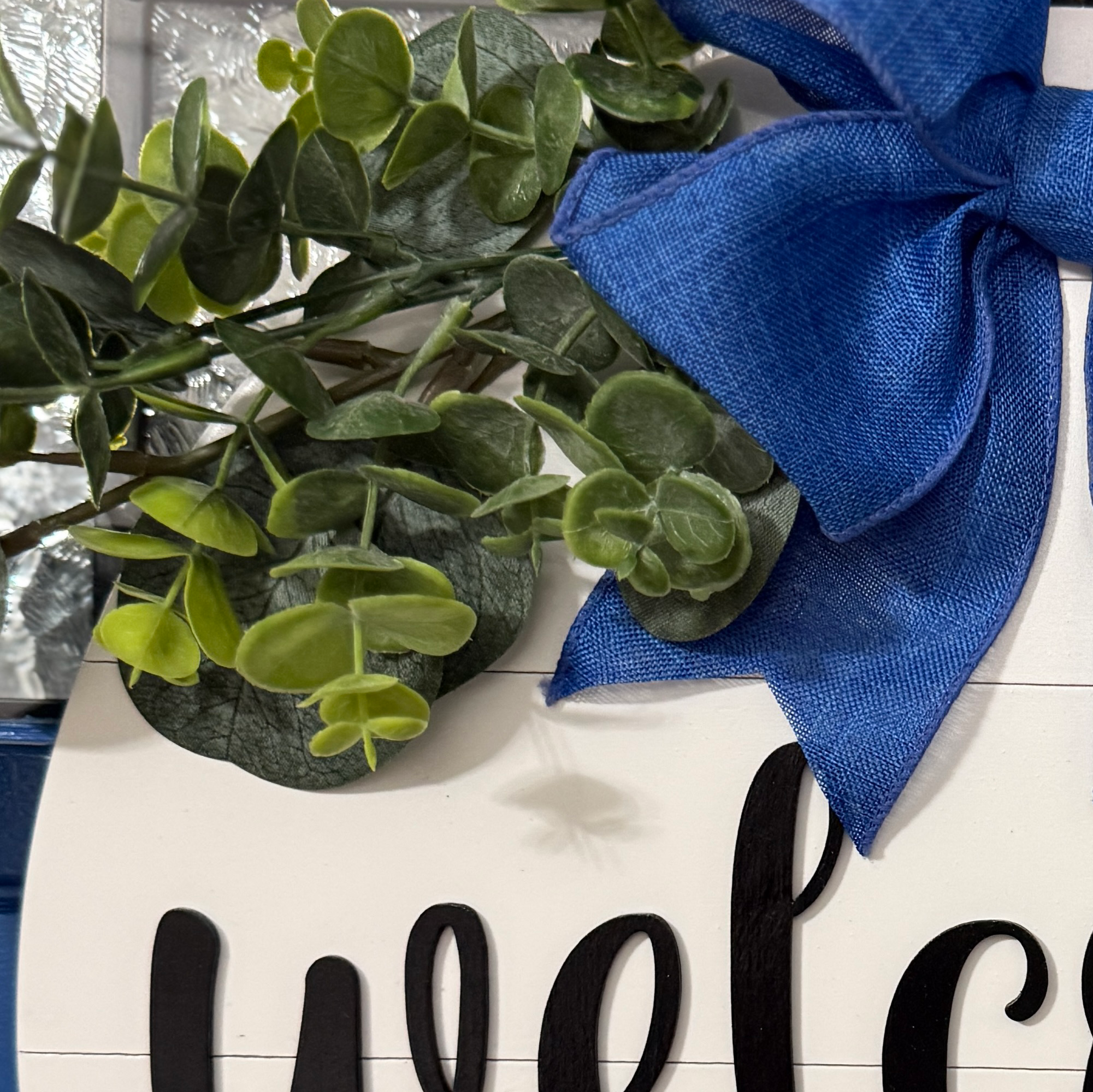 Farmhouse front door décor with bluebonnets, greenery, and blue bow