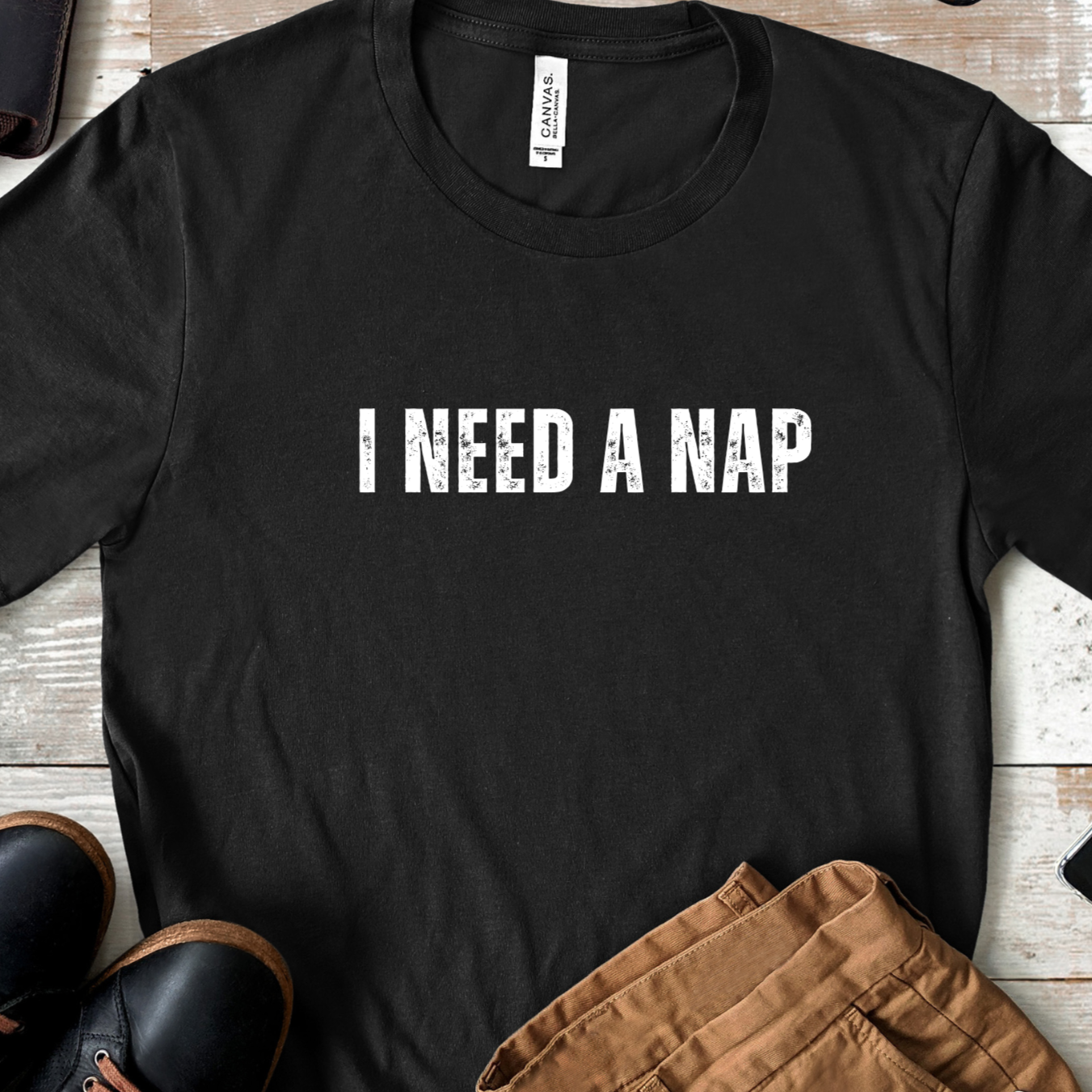 Flat lay of black unisex t shirt with i need a nap text