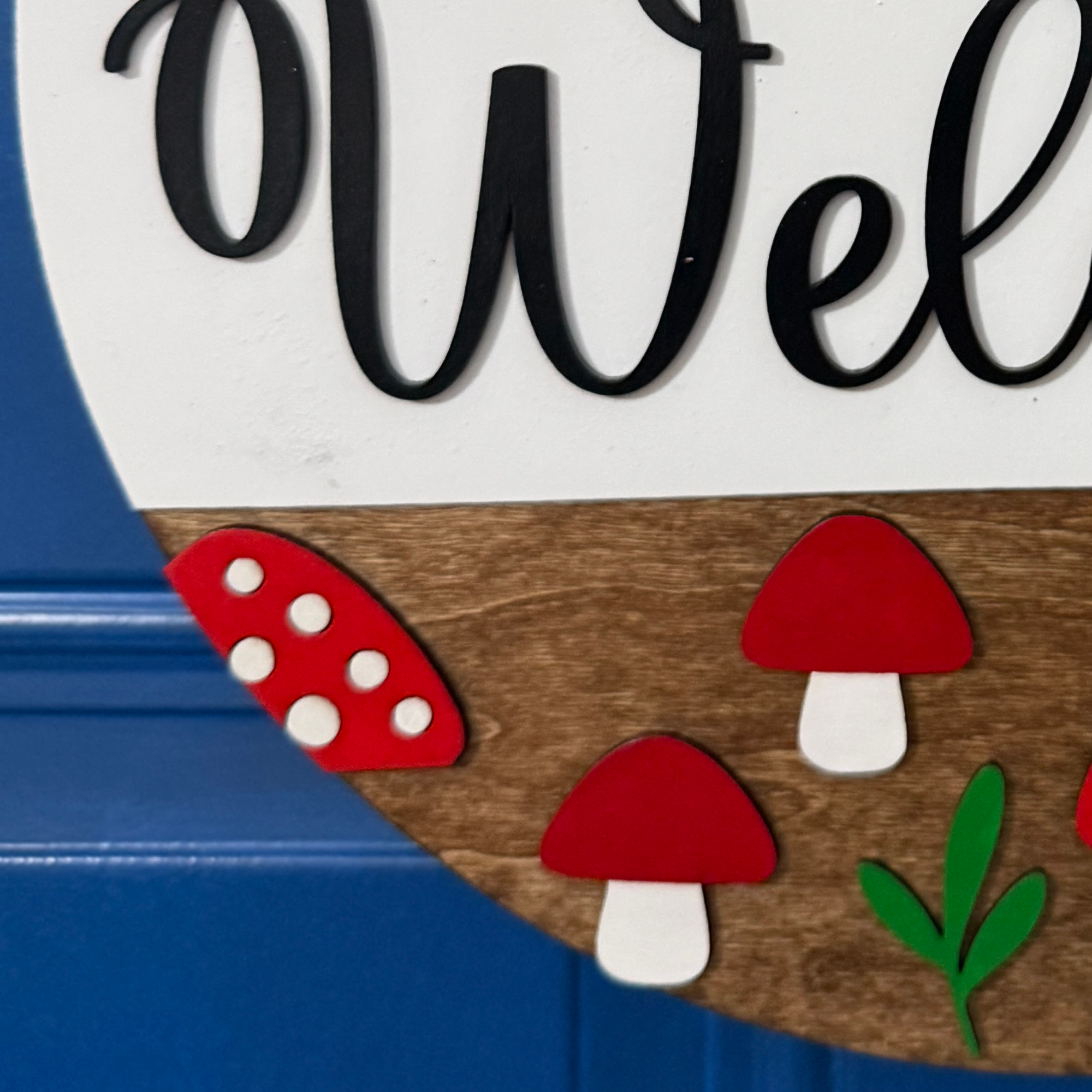 Layered red mushroom accents on stained wood and white shiplap welcome sign