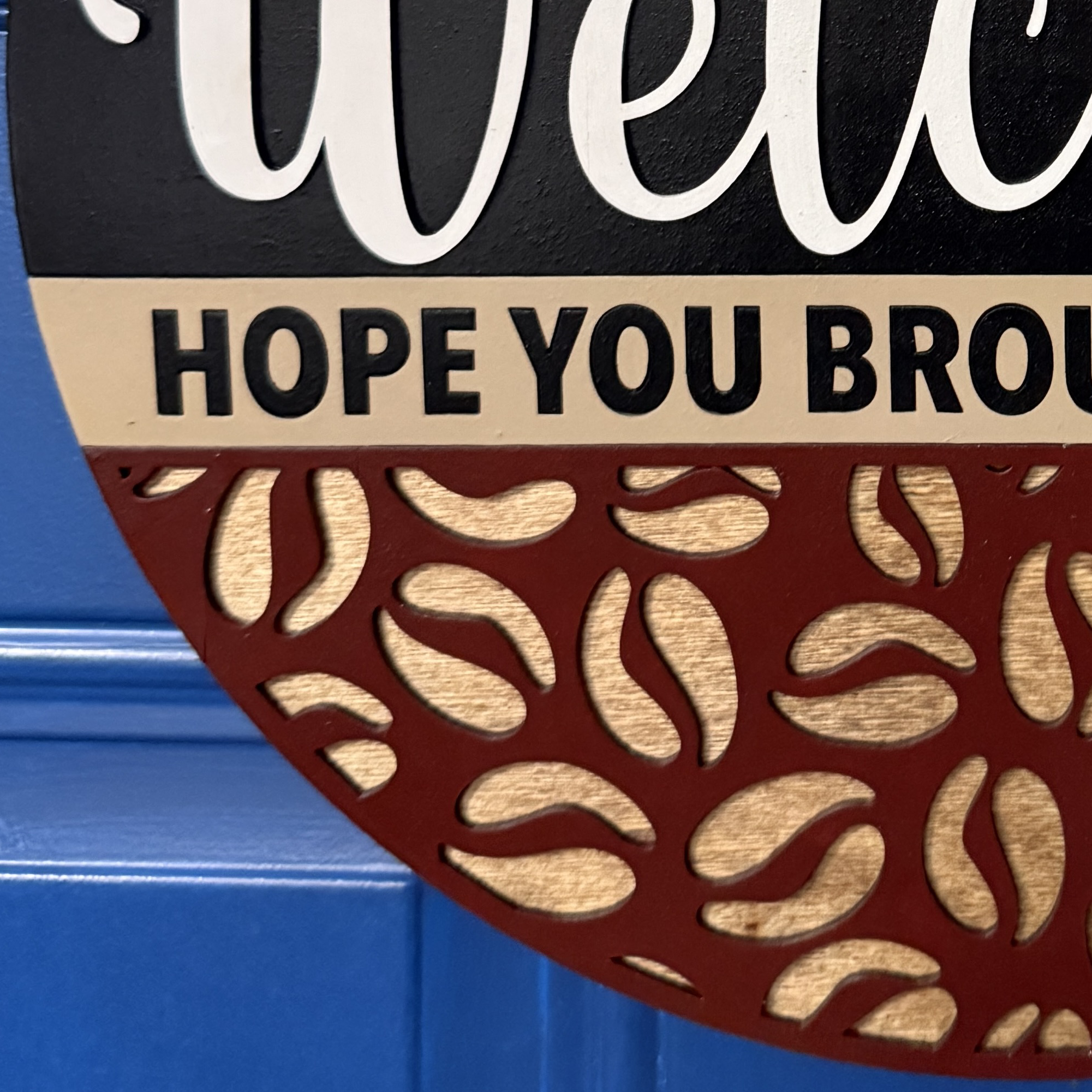 Close-up of lower half of sign with textured coffee bean pattern and wood grain