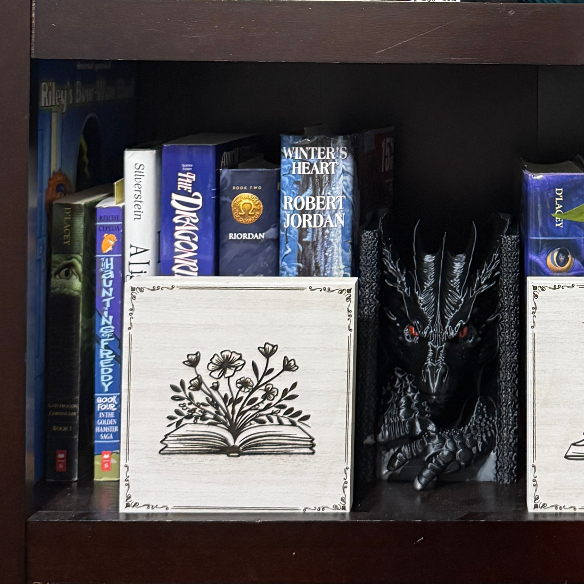Fairy book shelf sitter displayed on a bookshelf alongside fantasy novels and dragon decor, highlighting engraved floral book artwork