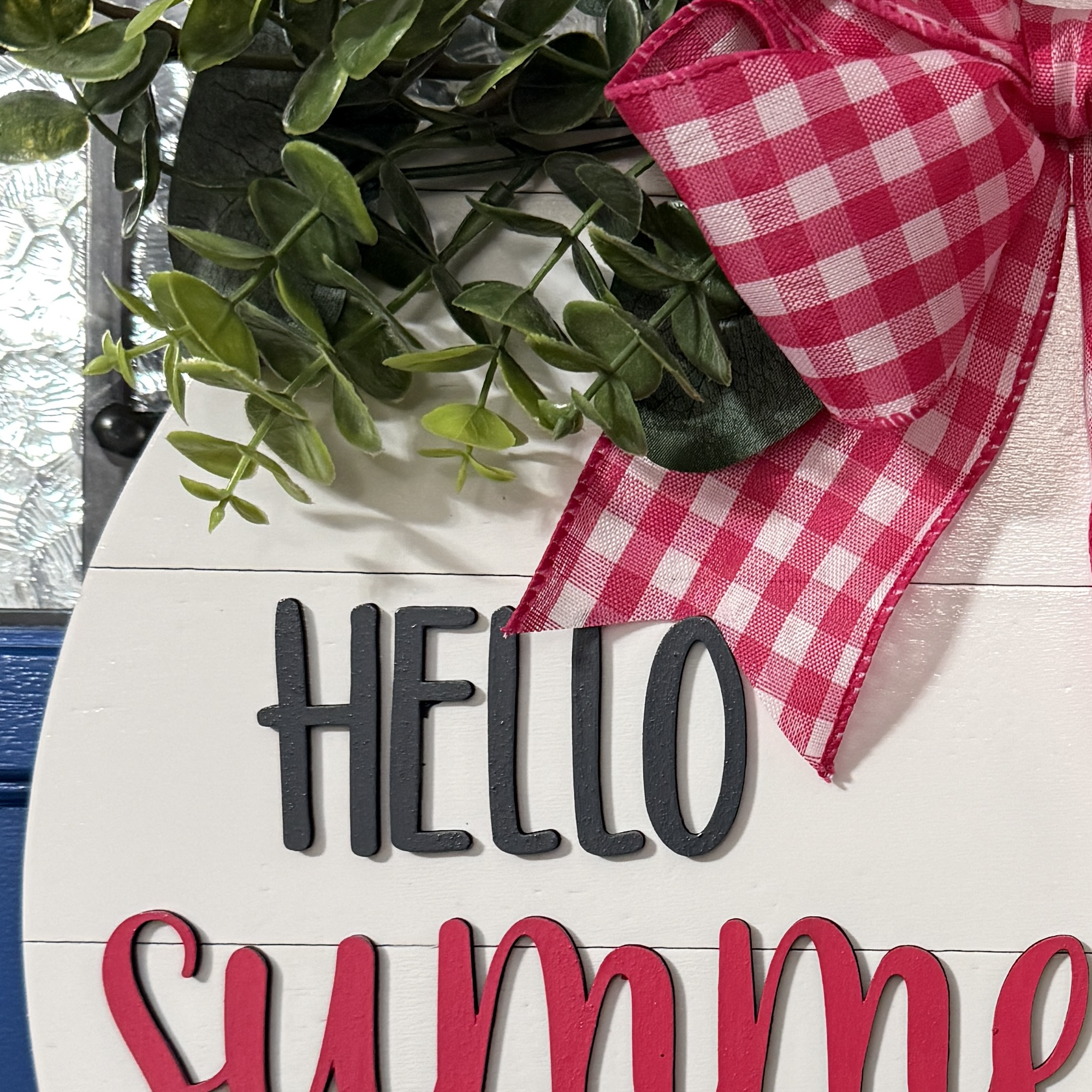 Close-up of charcoal “HELLO” and raised red “Summertime” script on white shiplap-style background