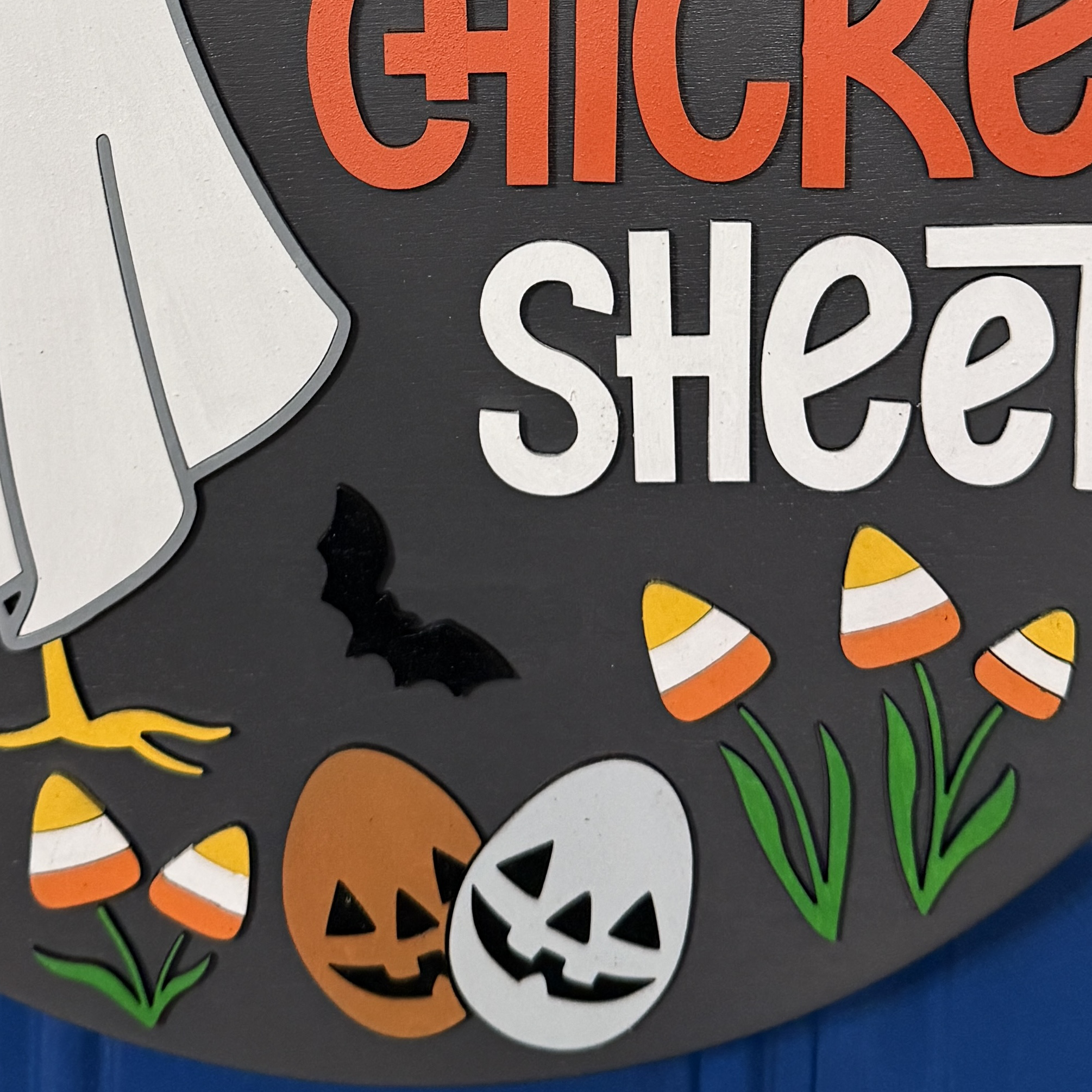 Close-up of ghost chicken character, candy corn, and jack-o’-lantern accents on the Halloween door hanger