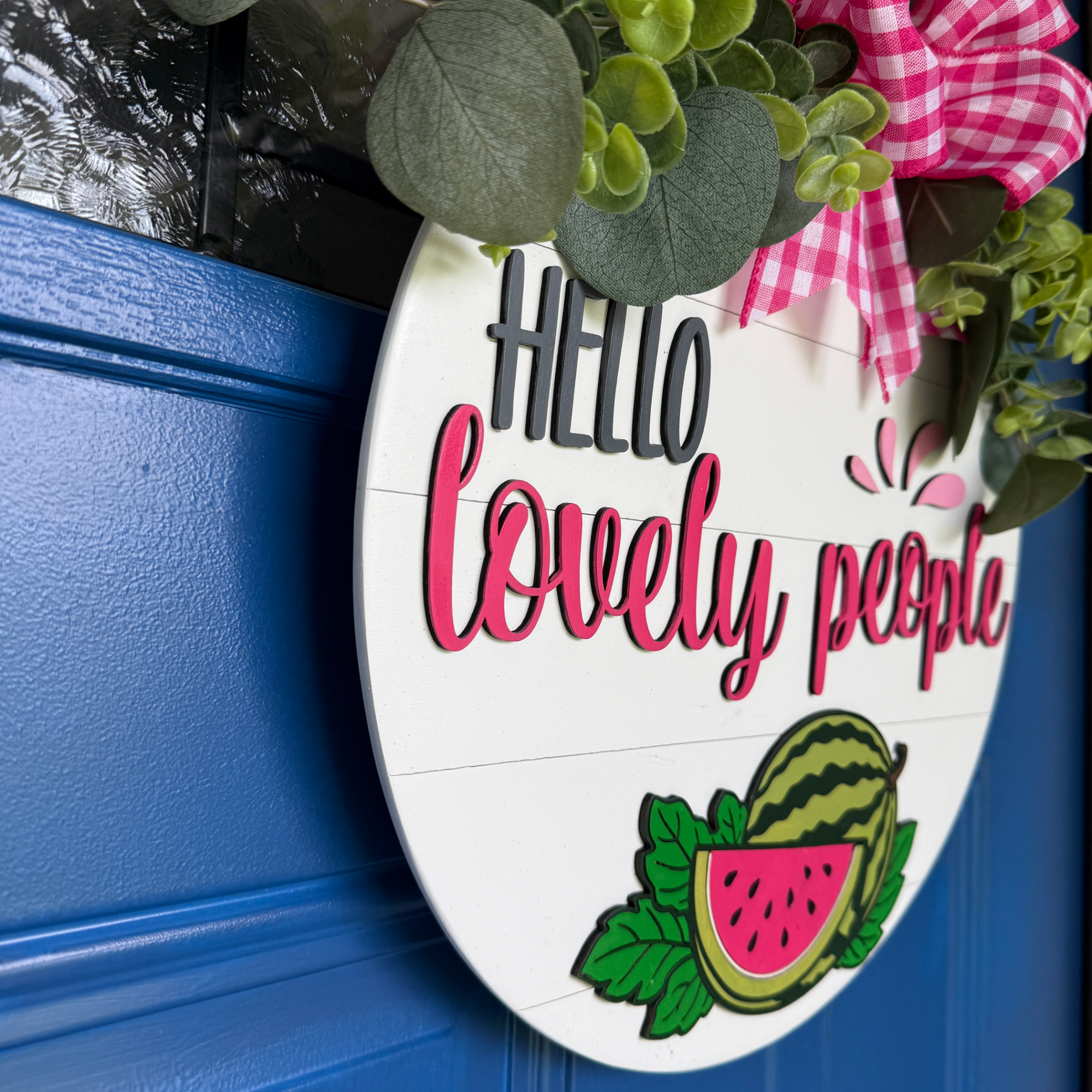 Layered wood watermelon door hanger featuring Hello Lovely People text, shown from an angled side view highlighting dimensional details.