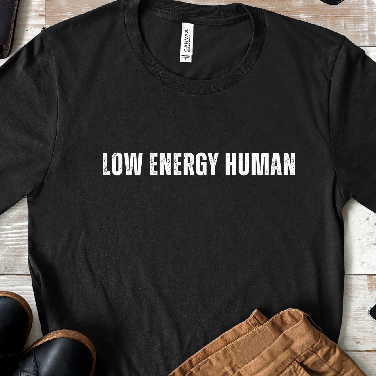 Flat lay of black unisex t shirt with low energy human text