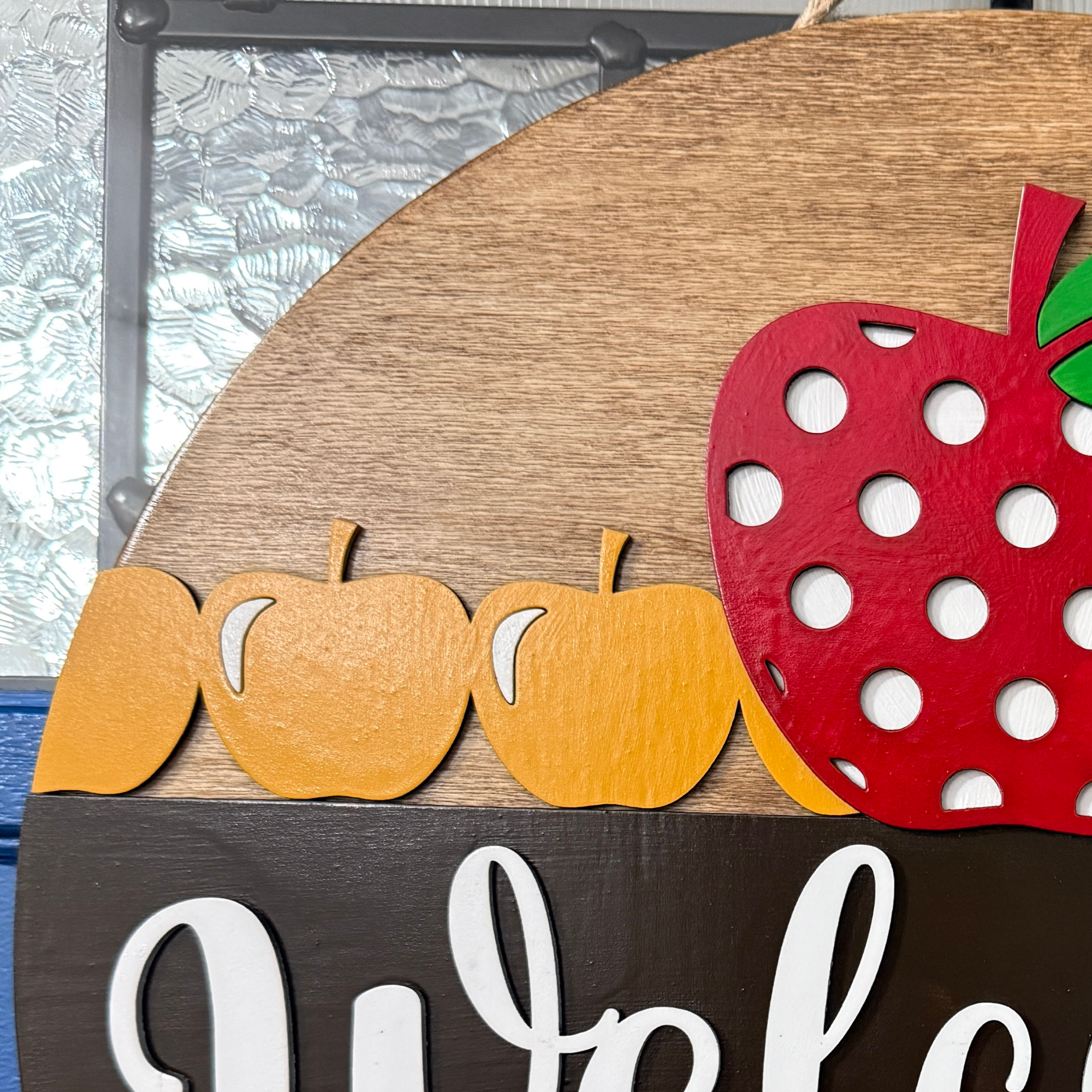 Close-up of top section with red apple and row of yellow apples on wood background