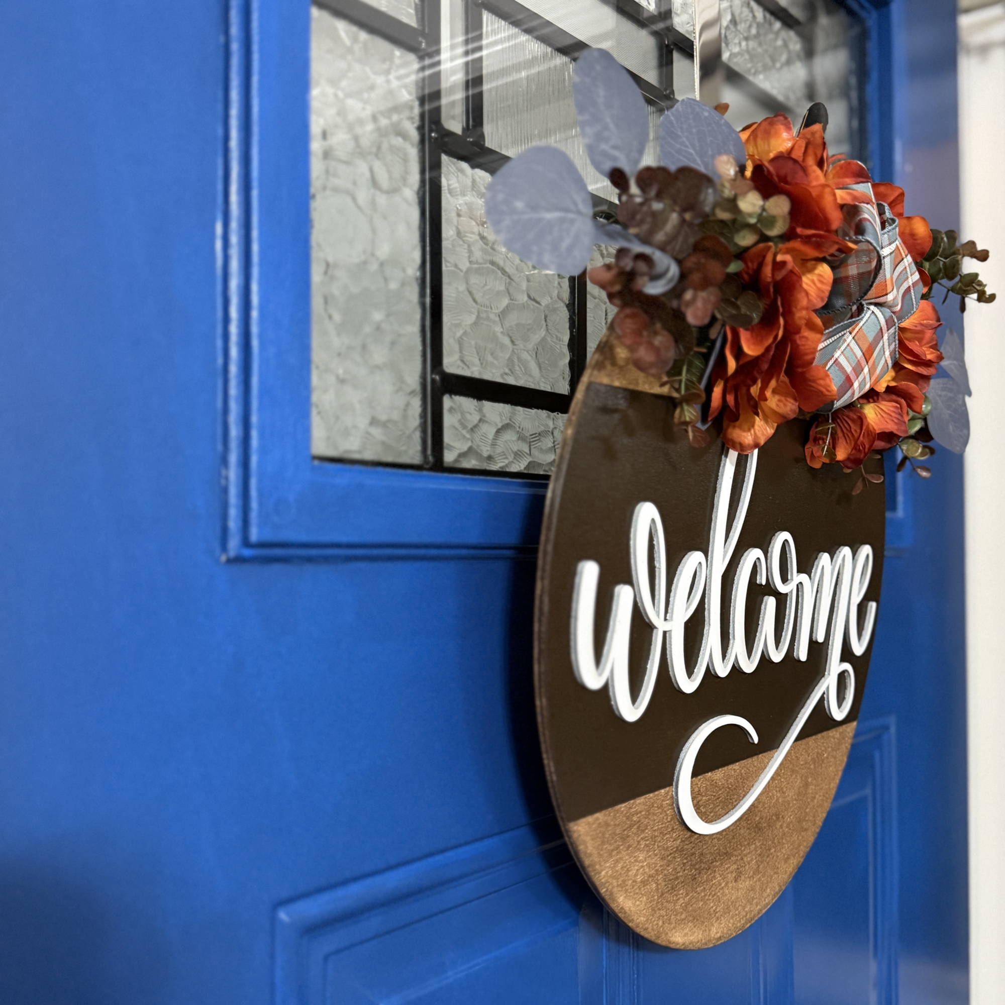 Side view of “welcome” lettering and layered floral accents on autumn door hanger