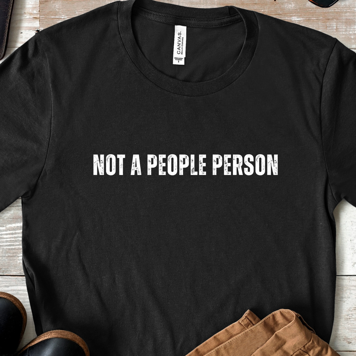 Flat lay of black not a people person graphic t shirt with centered text