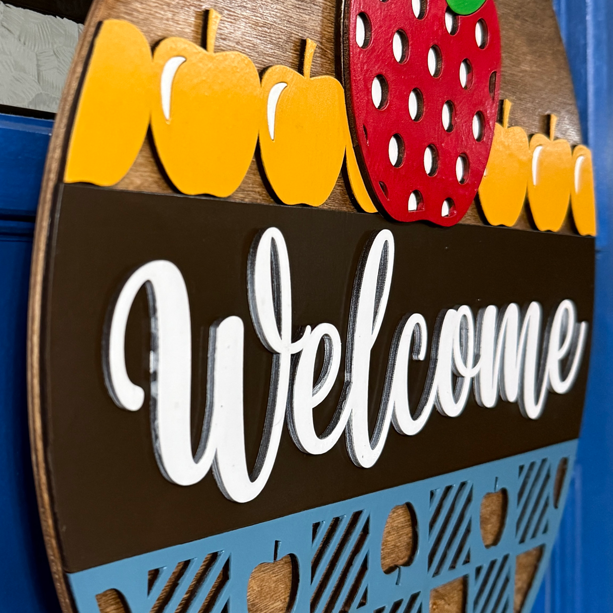 Side angle detail of layered apples and lettering showing dimensional wood elements
