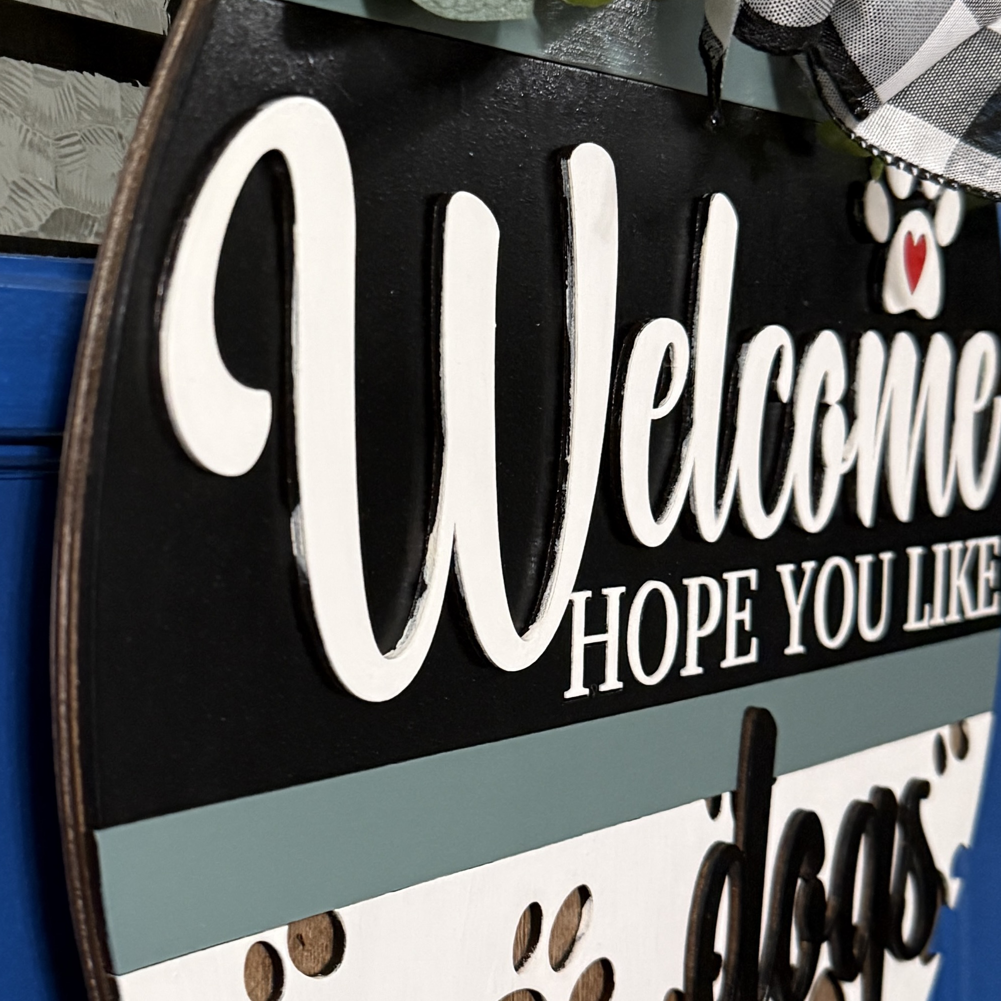 Side angle of welcome sign showing dimensional lettering and painted wood layers