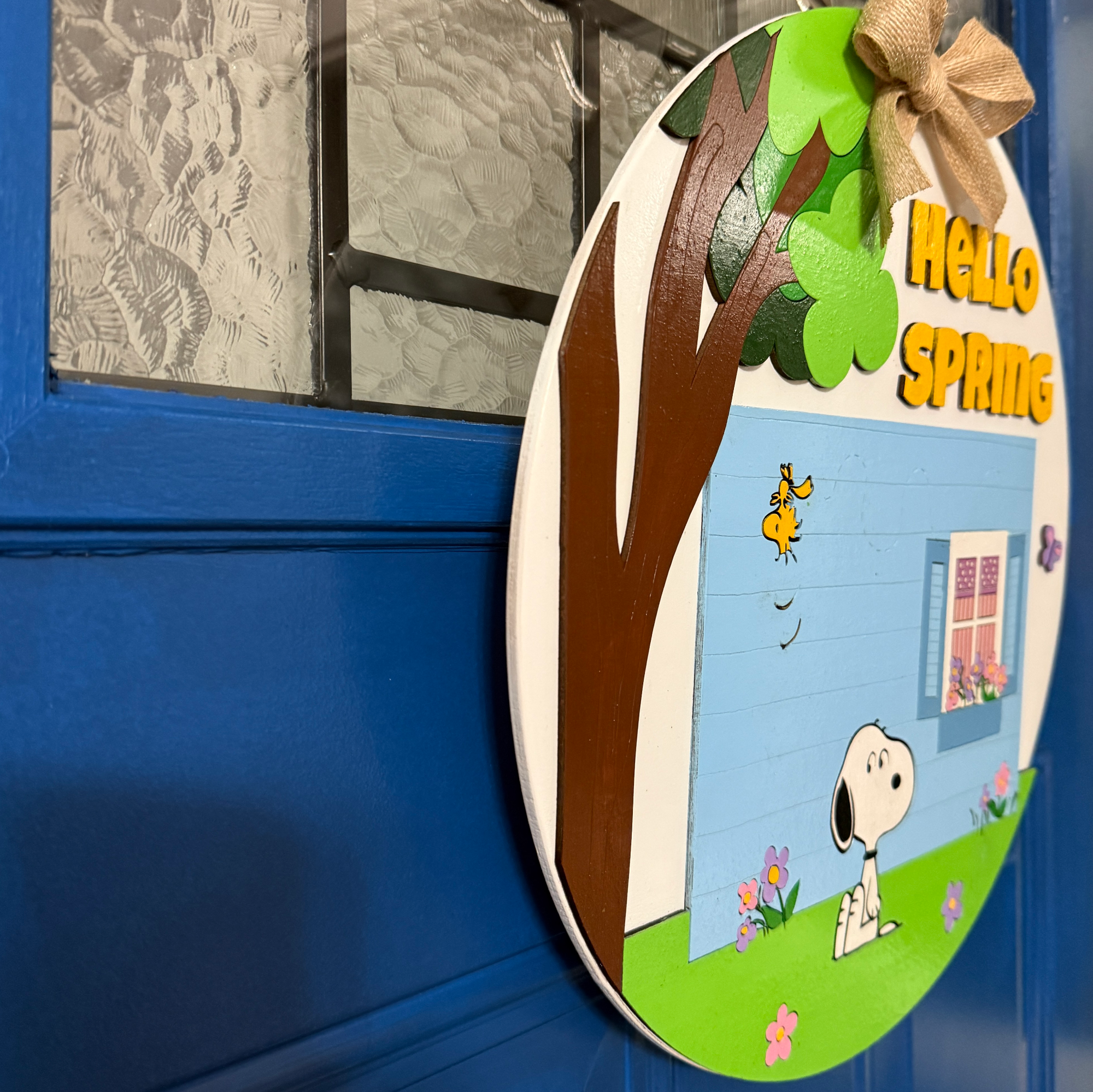 Angled side view of spring door hanger showing layered wood design and dimensional elements