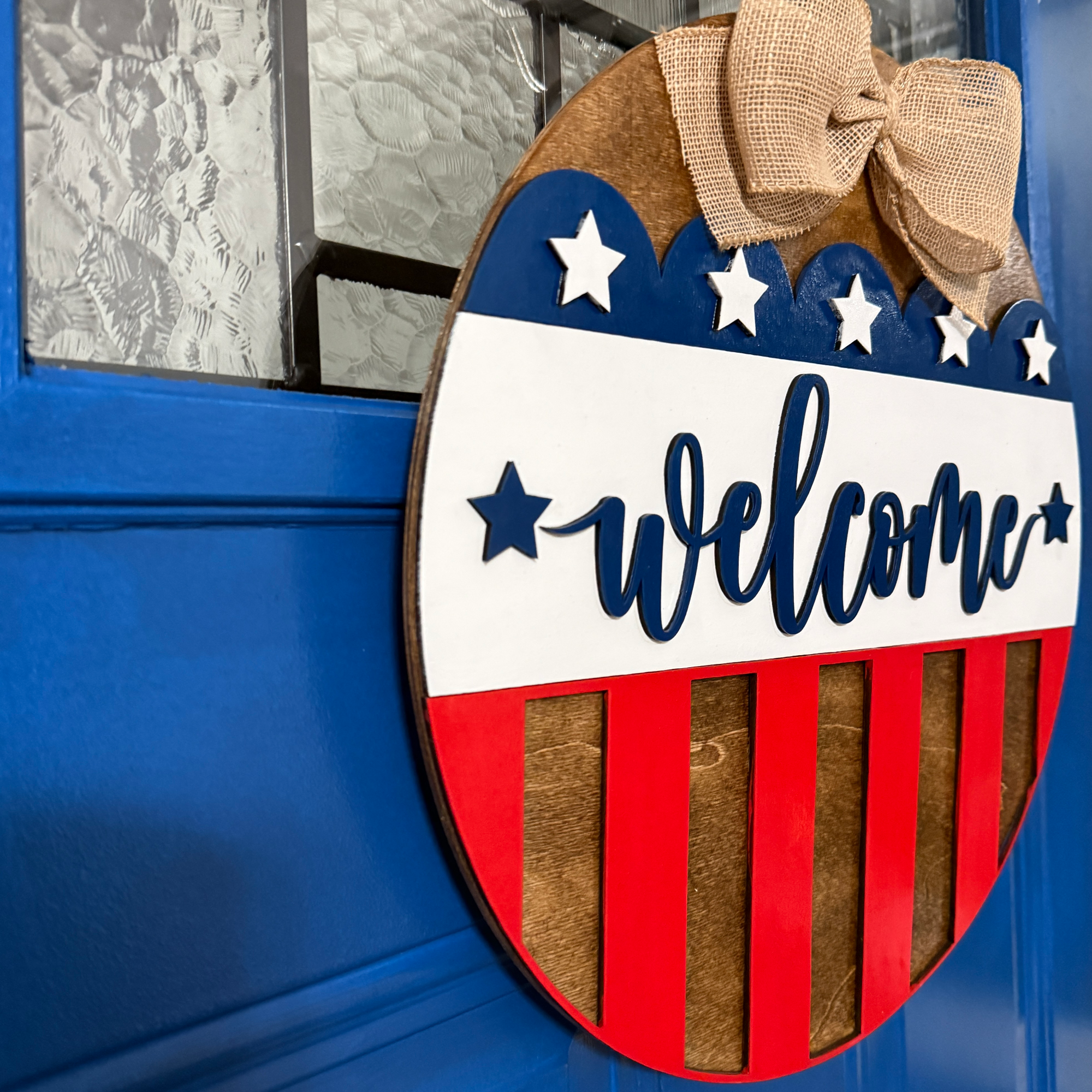 Side view of patriotic welcome wood door hanger showing dimensional layered construction.
