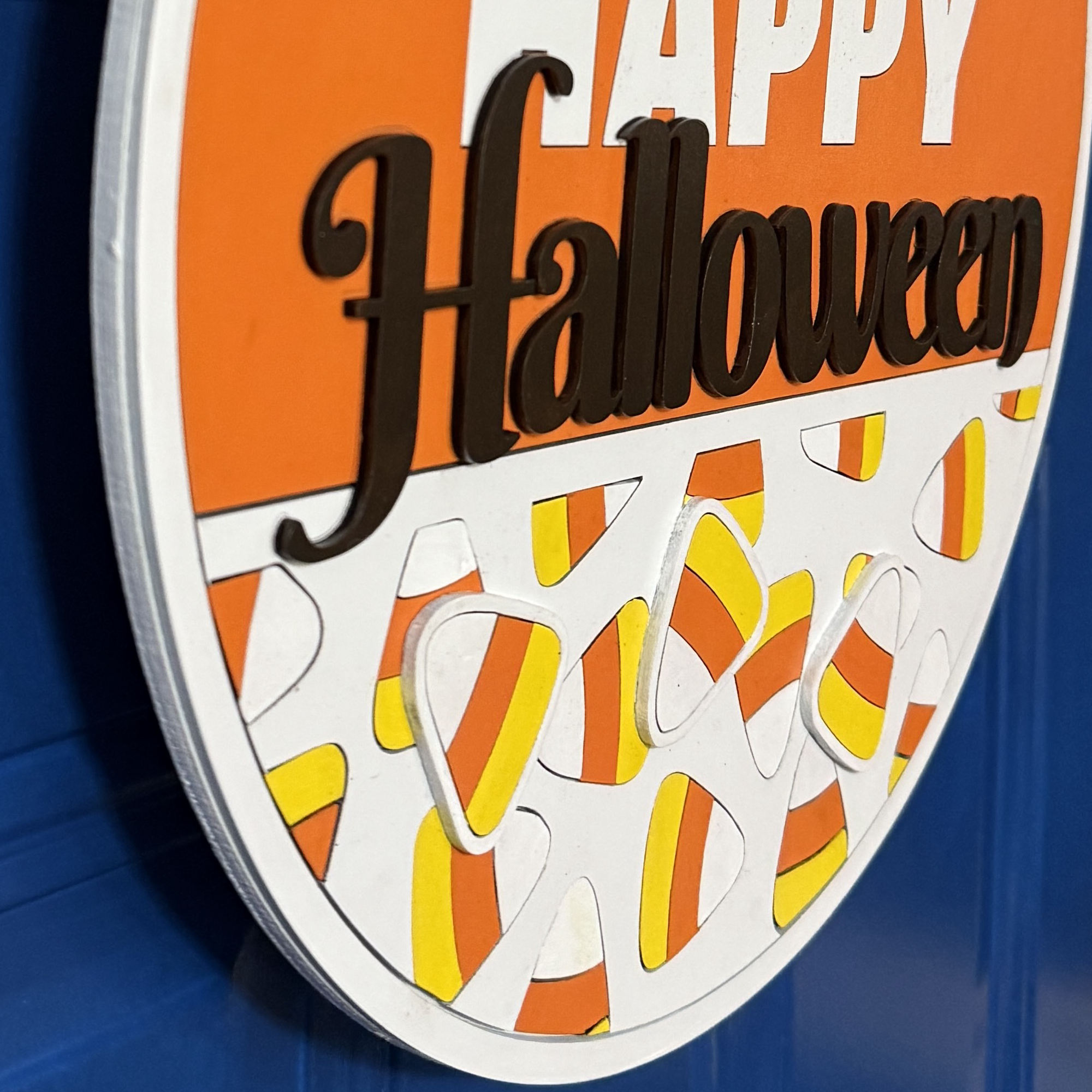 Close-up of Halloween candy corn door hanger with bow, hanging on a blue front door