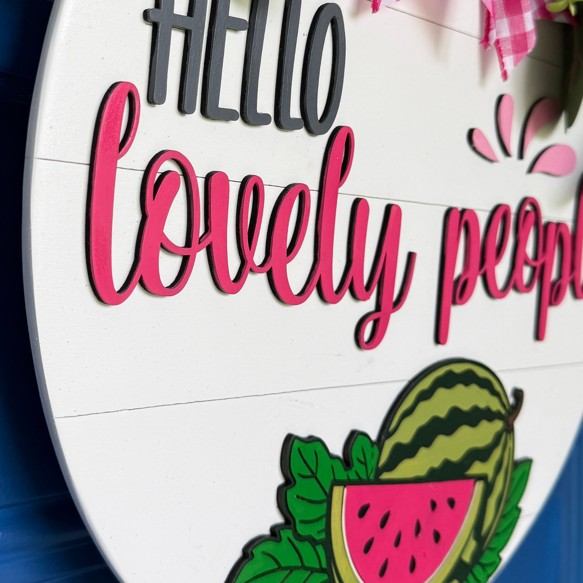 Angled close-up showing dimensional layered wood construction and painted details of a watermelon door hanger.