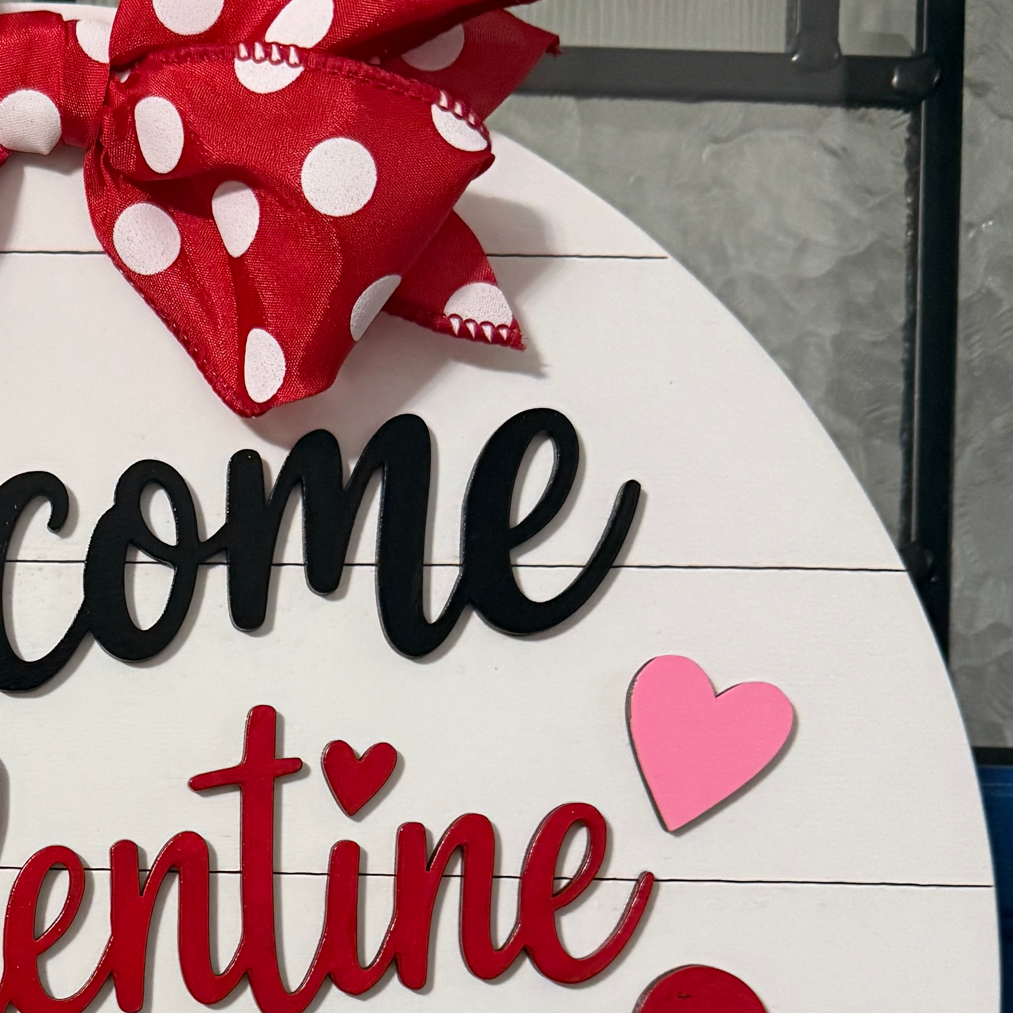 Close-up of dimensional black Welcome lettering and red polka dot bow on Valentine door hanger