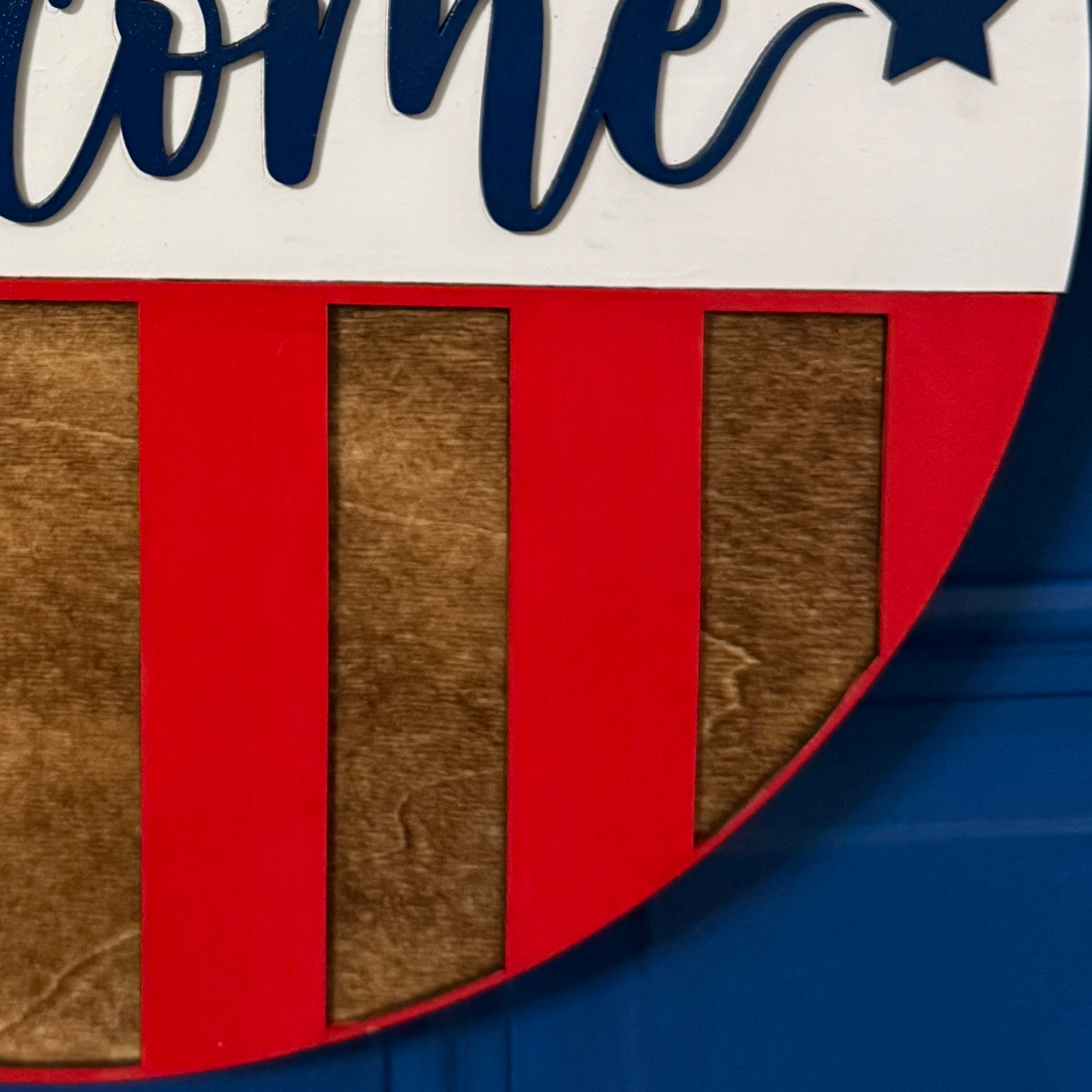 Close-up of stained wood and bright red vertical stripe accents on the lower half of the patriotic sign.