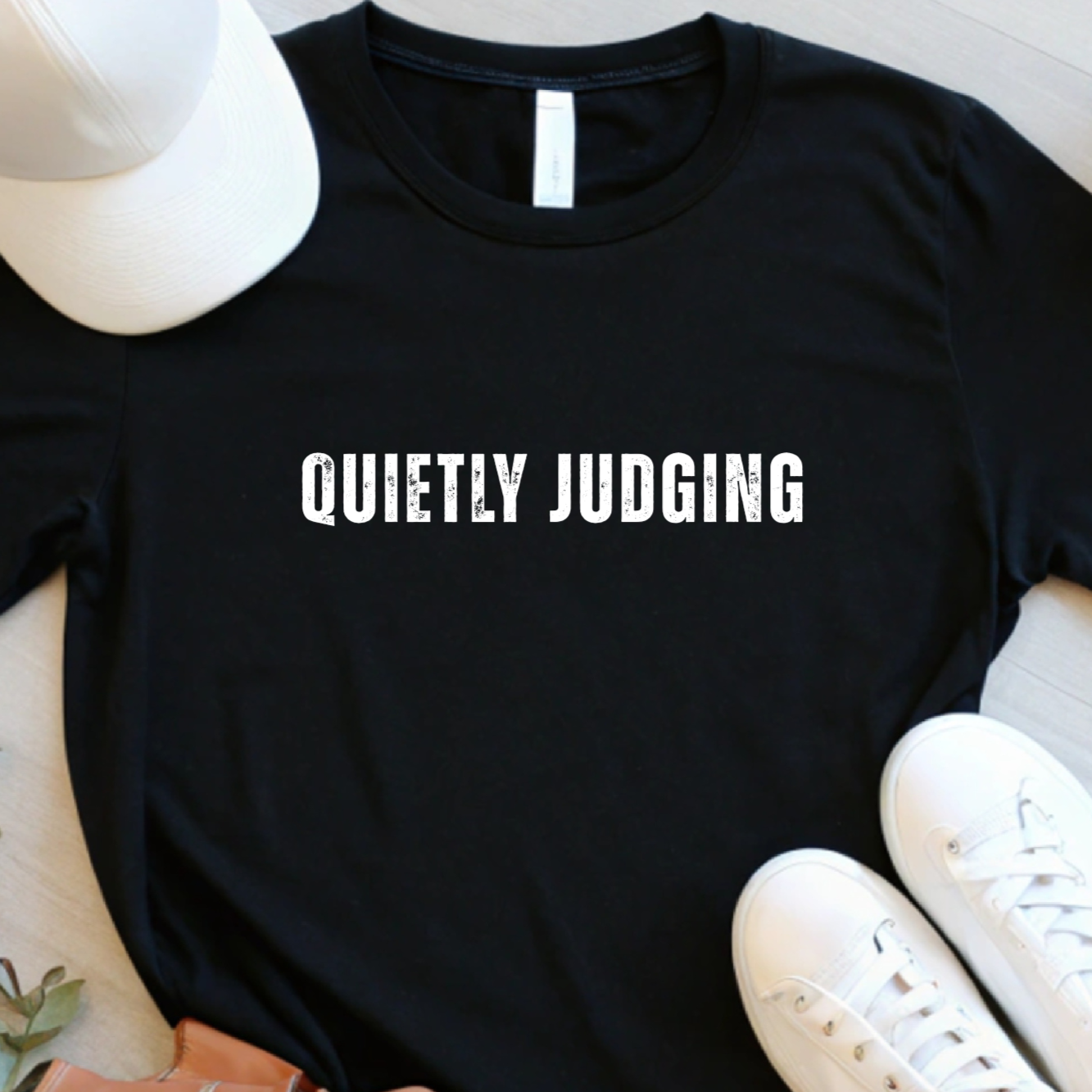 Flat lay of black quietly judging graphic t shirt with centered white text