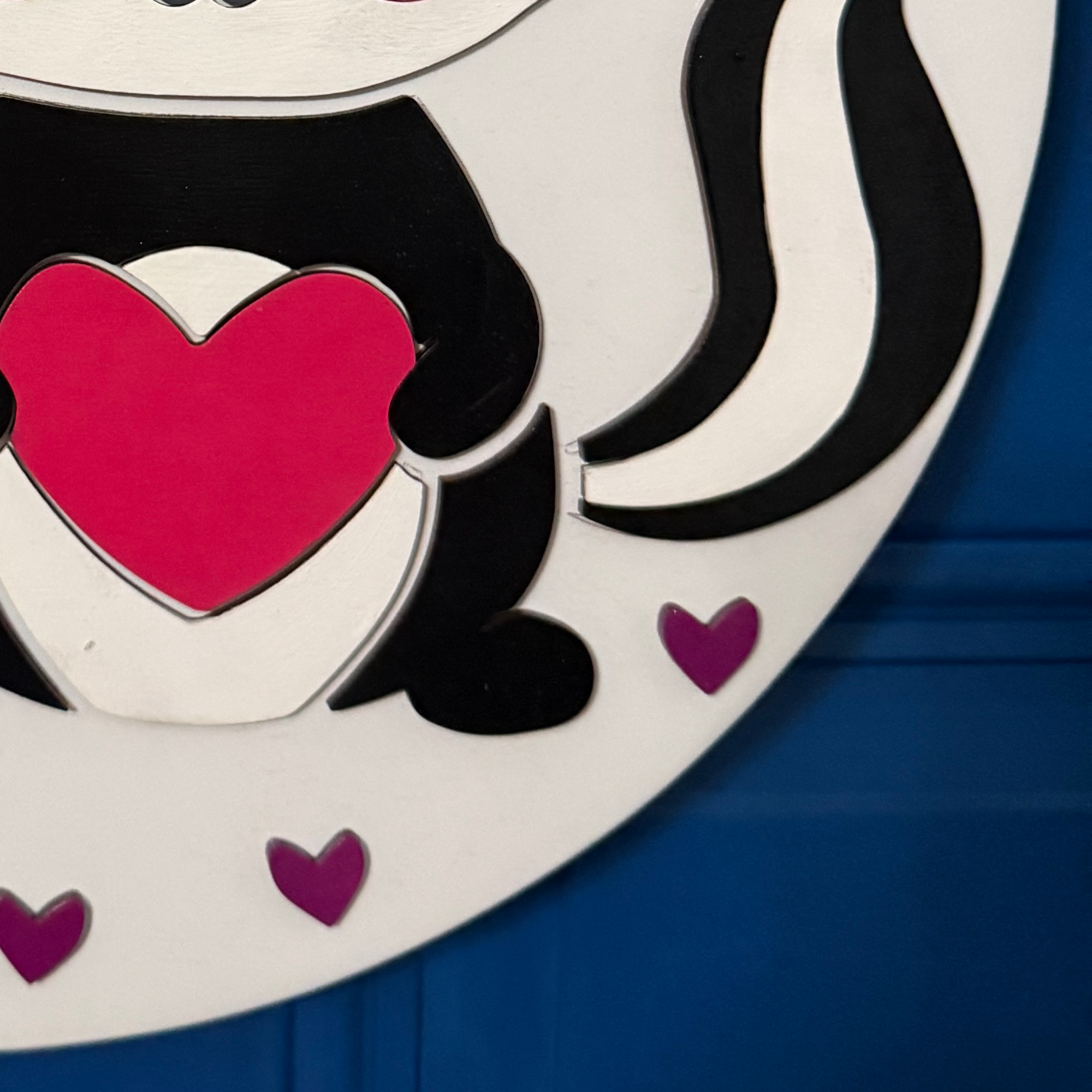 Close-up of layered skunk holding a bright pink heart with black and white striped tail