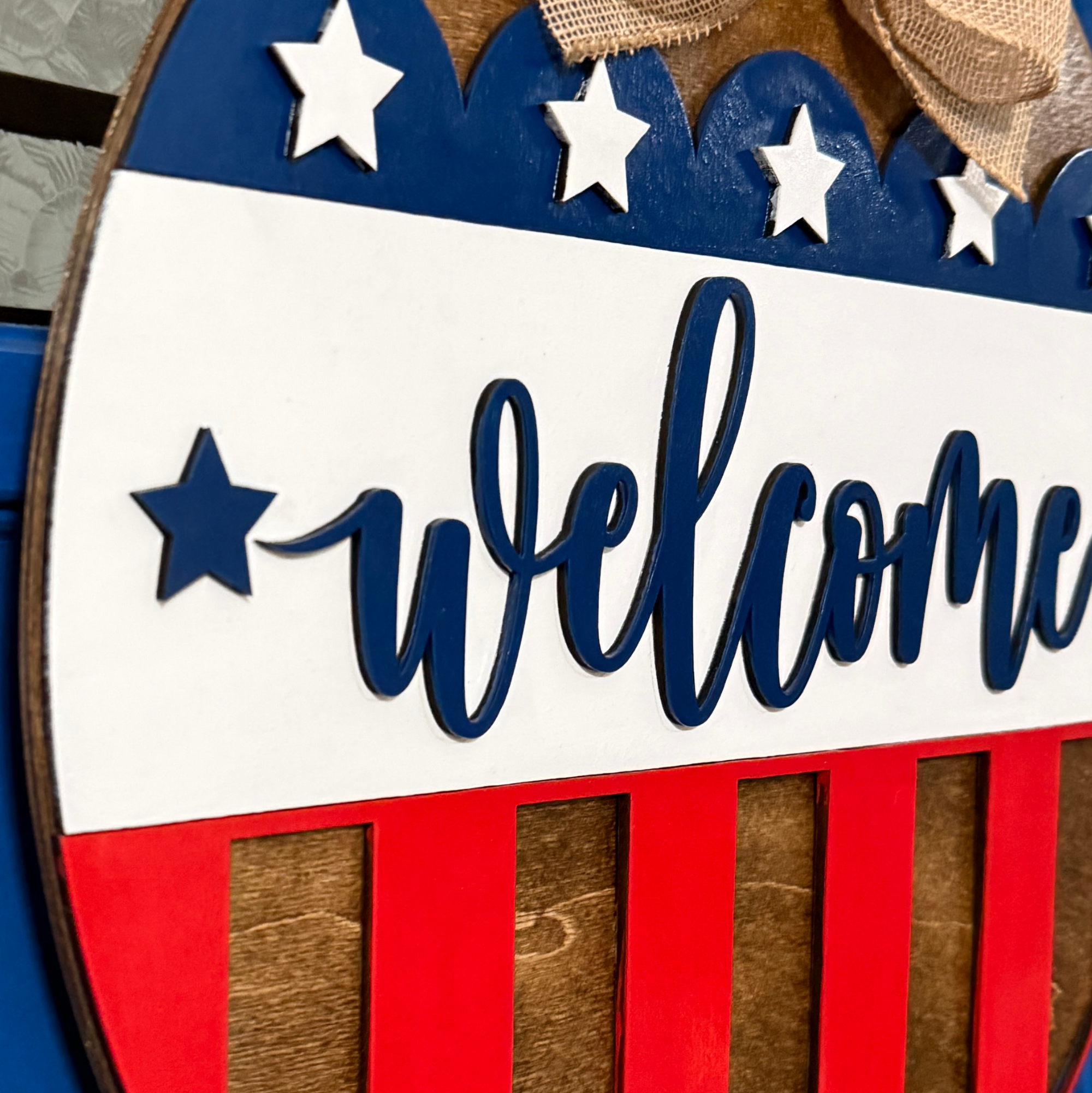 Angled side profile highlighting the layered welcome lettering and dimensional patriotic details.