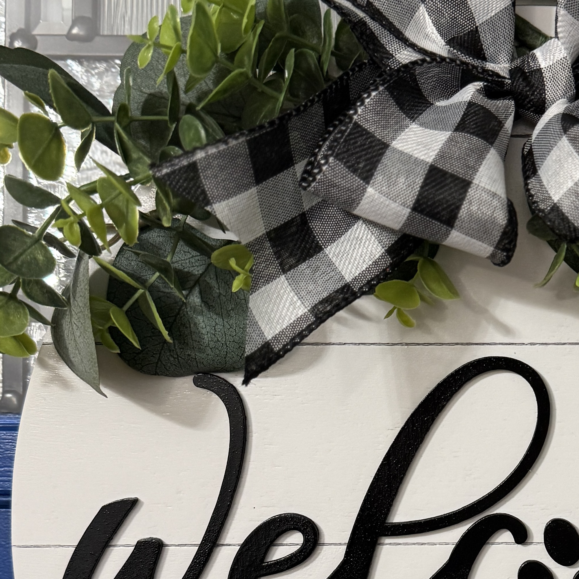 Close-up of greenery and bow detail with black and white ribbon loops
